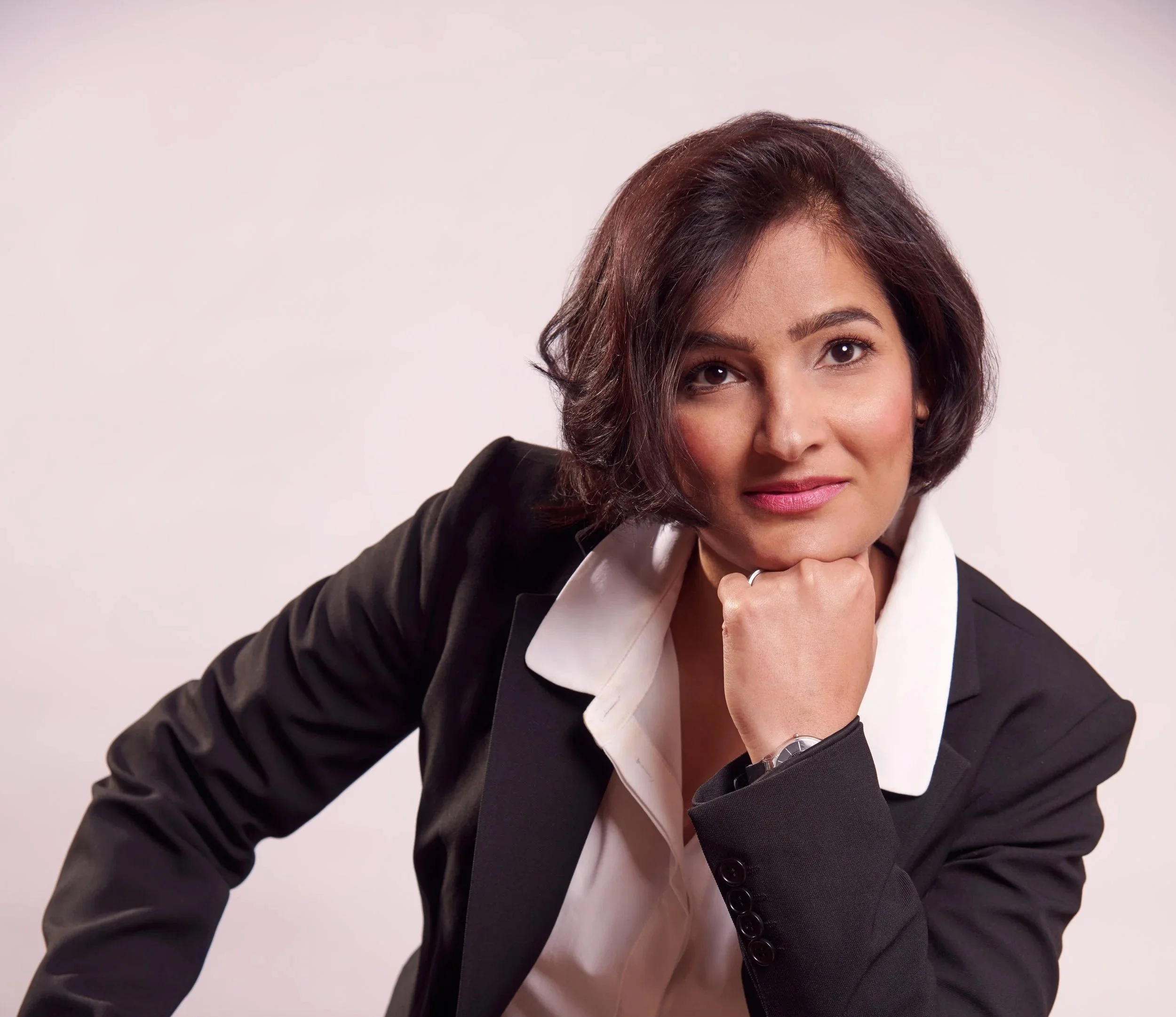 Nistha Trehun, founder of Kitty Party in Berlin, in a black blazer, resting her chin on her hand