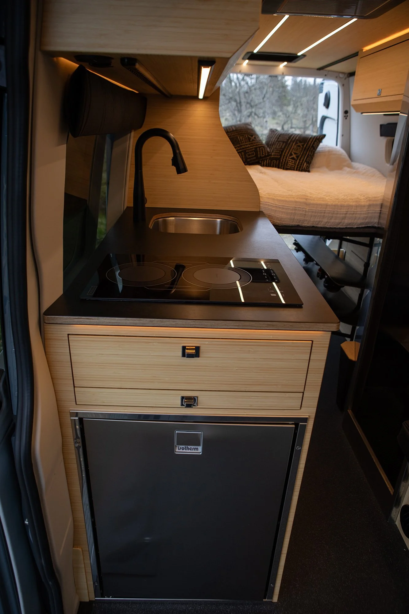 EAV Zephyr Adventure Van's Kitchen area with the bed setup in the background.