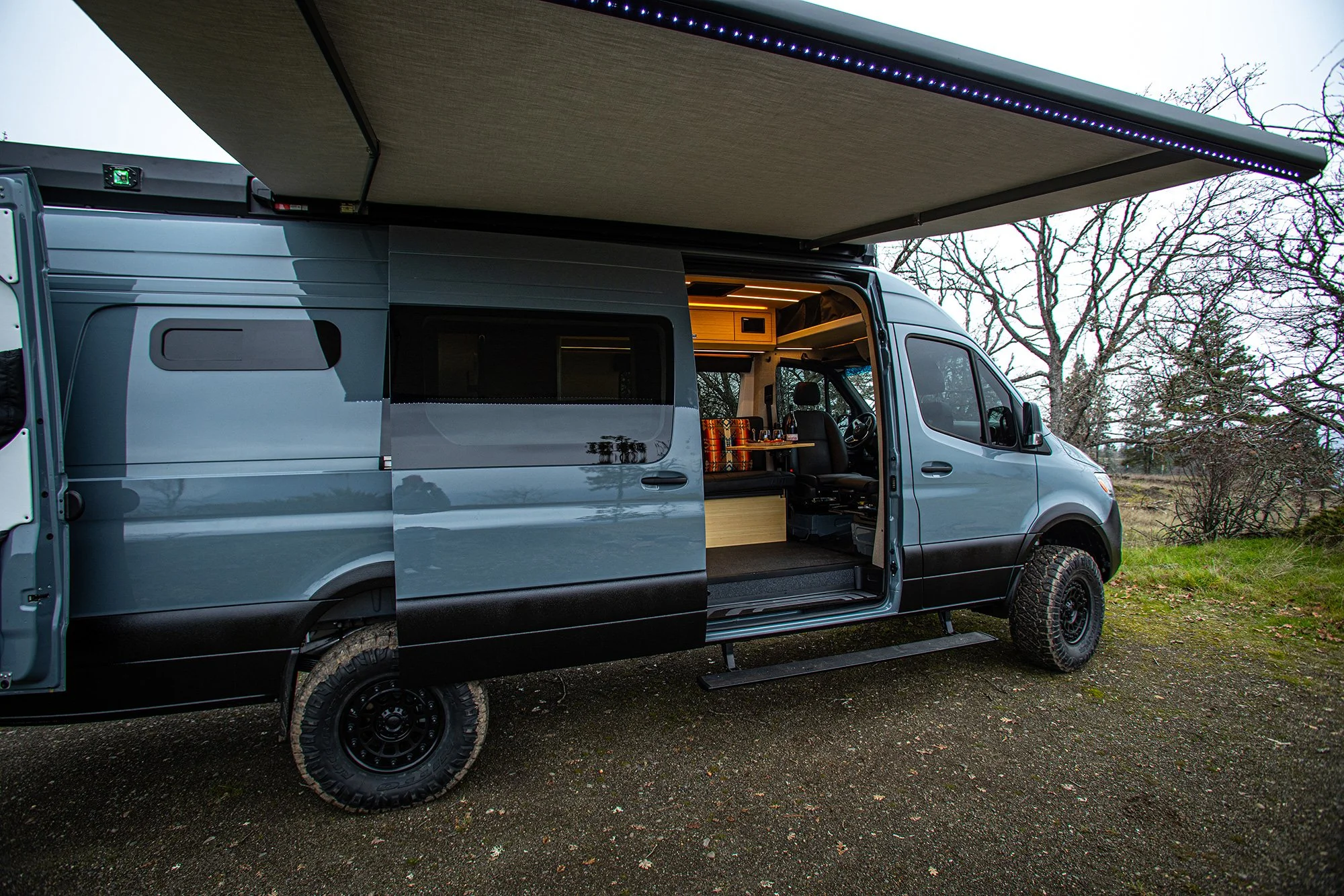EAV Zephyr adventure van with it's awning out and side and back doors open.