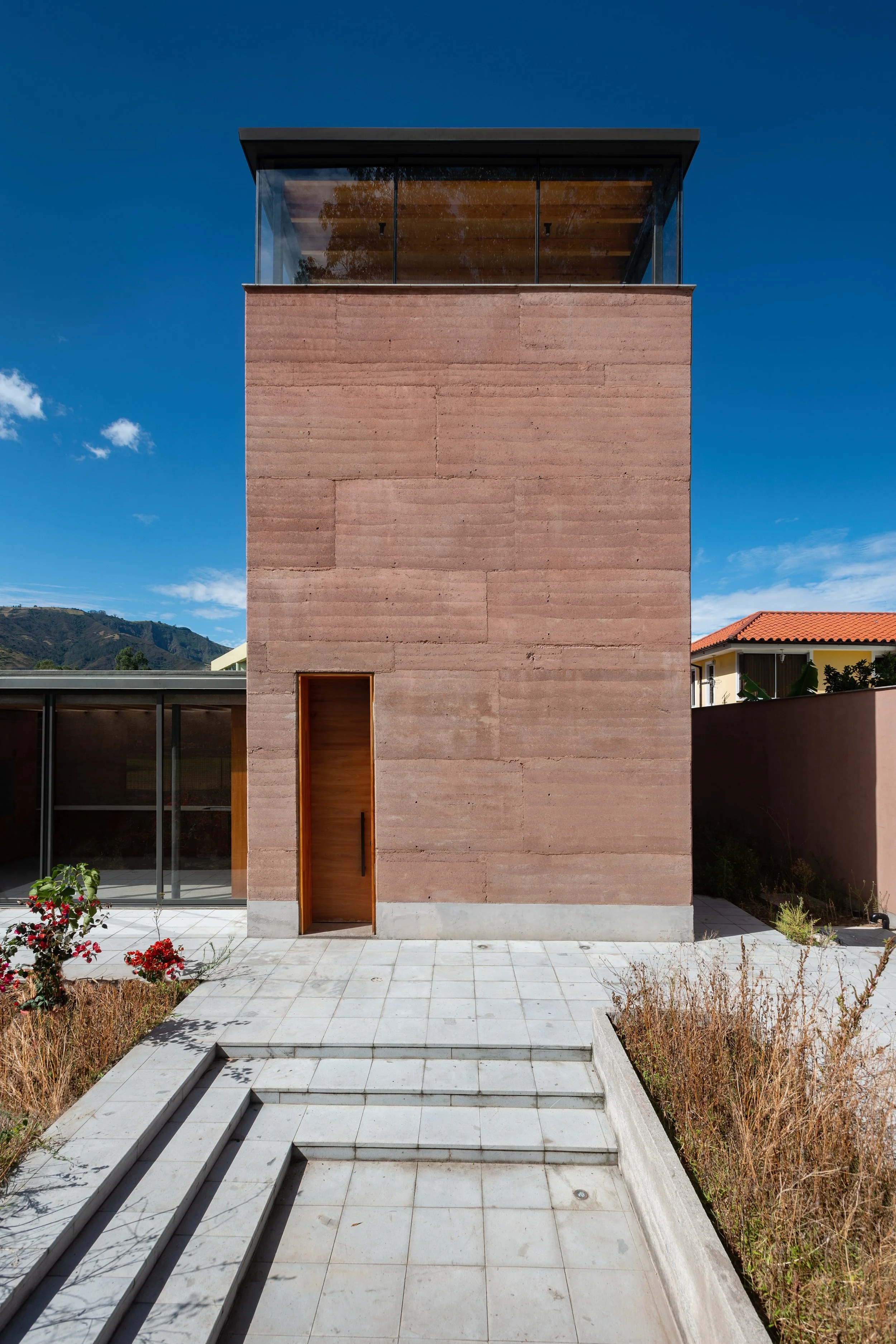  Schmale, dreigeschossige Straßenfront aus Stampflehmwänden, links daneben befindet sich die Küche mit raumhoher Verglasung 