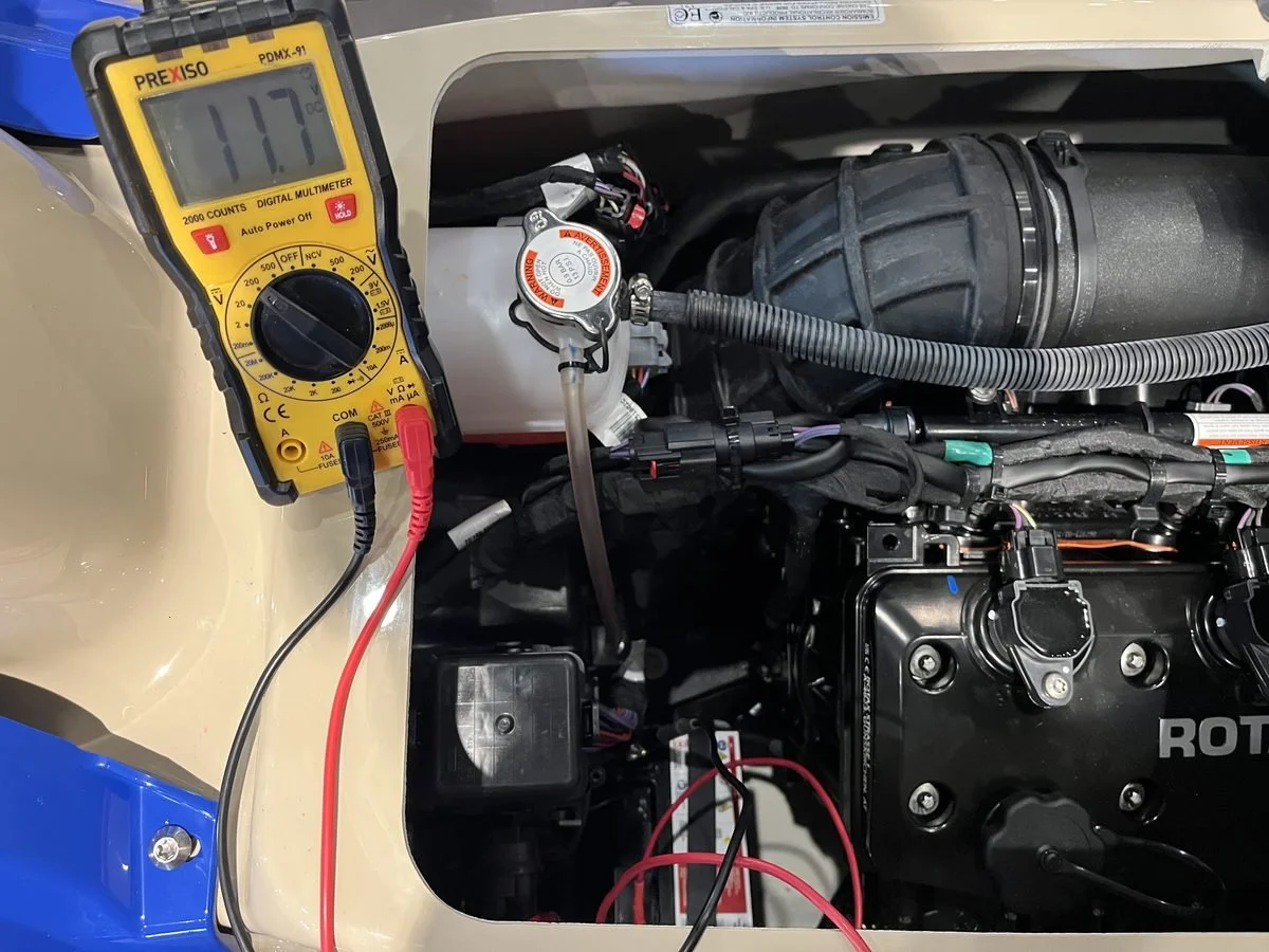 Testing Sea-Doo battery voltage with a multimeter — 11.7V reading indicates the battery needs charging
