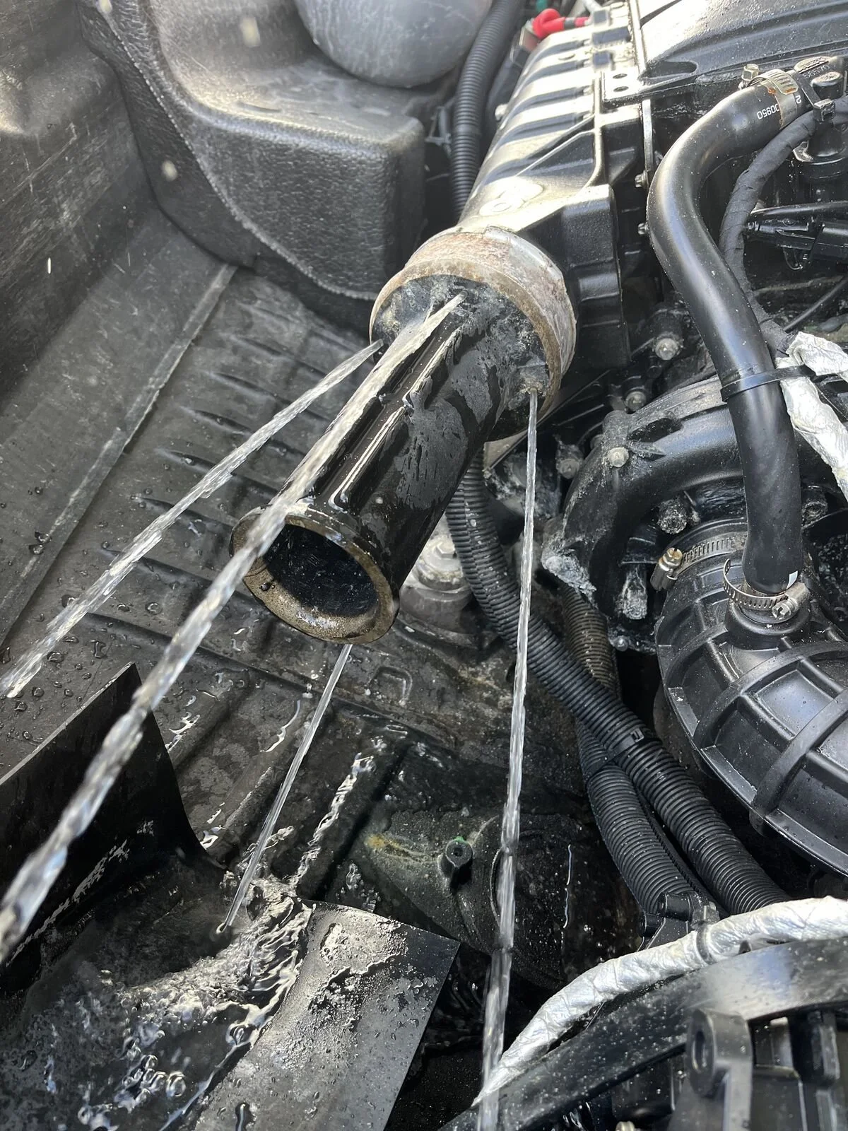 Water spraying from the cooling water injection point after the exhaust manifold on a Sea-Doo, shown with the waterbox removed