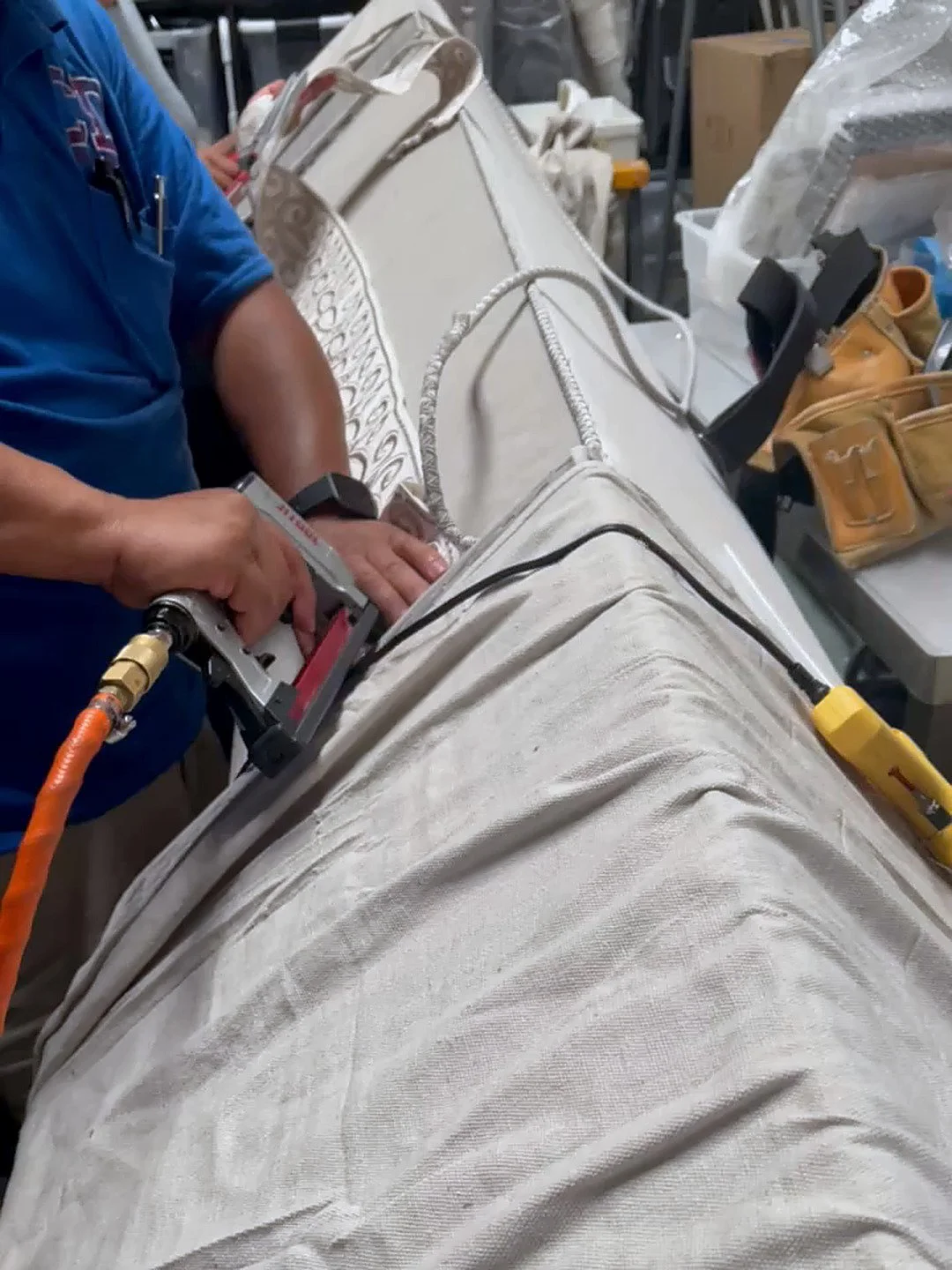 Artisan upholstering a custom cornice with decorative trim in the workroom for LUXYSPACE