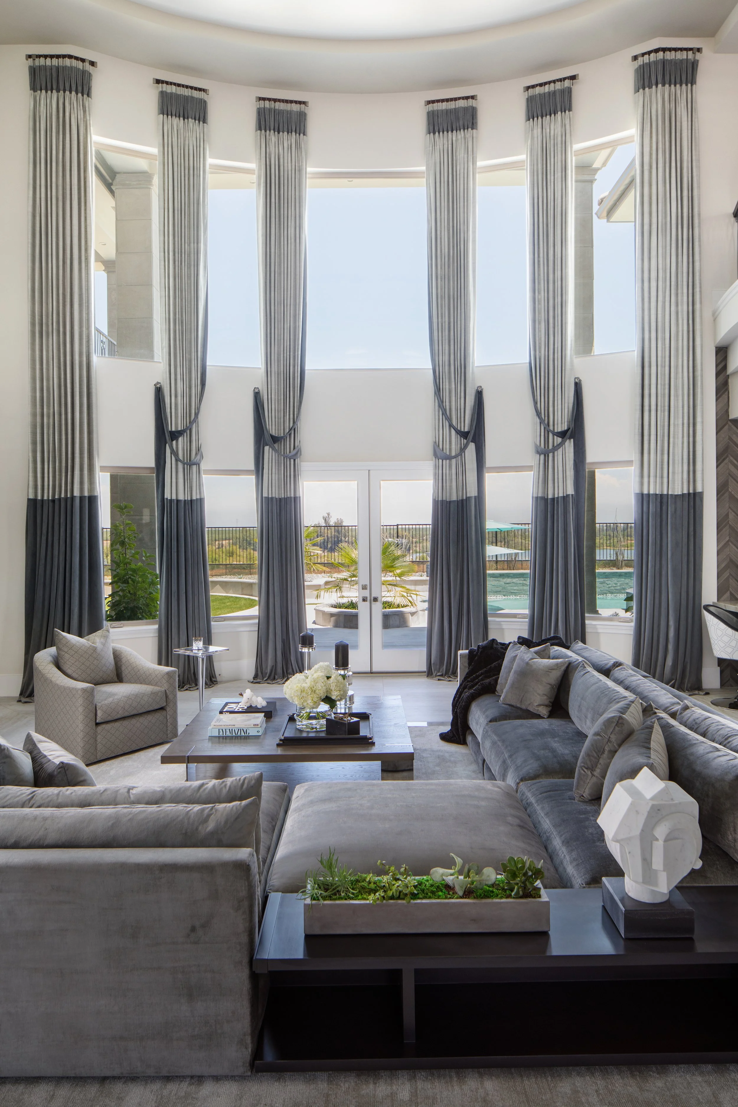 Double-height great room with gray velvet sectional and custom drapery designed by LUXYSPACE, Mission Viejo interior designer