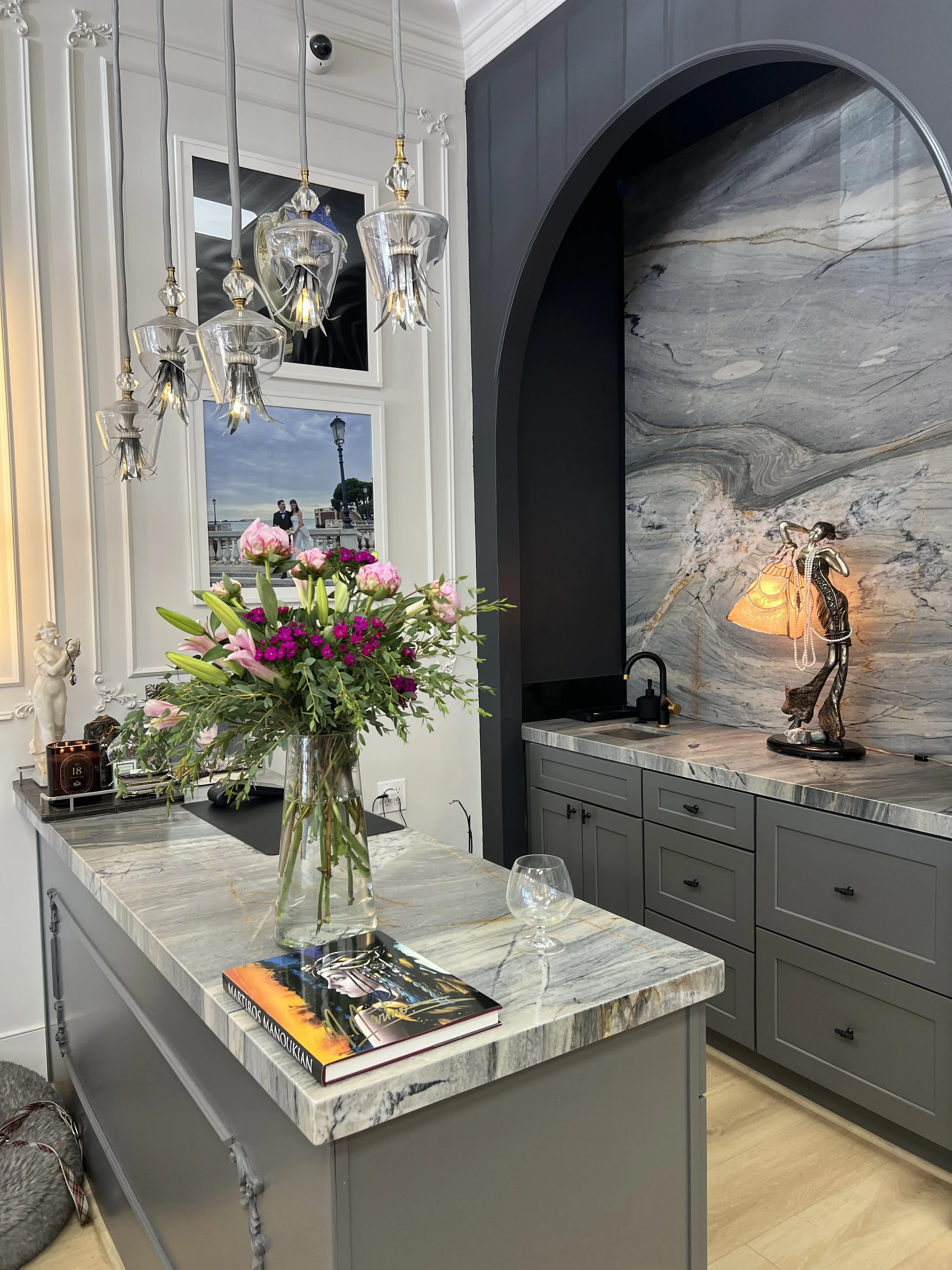 Client bar with full quartzite slab in arched niche, quartzite counters and glass pendant lights