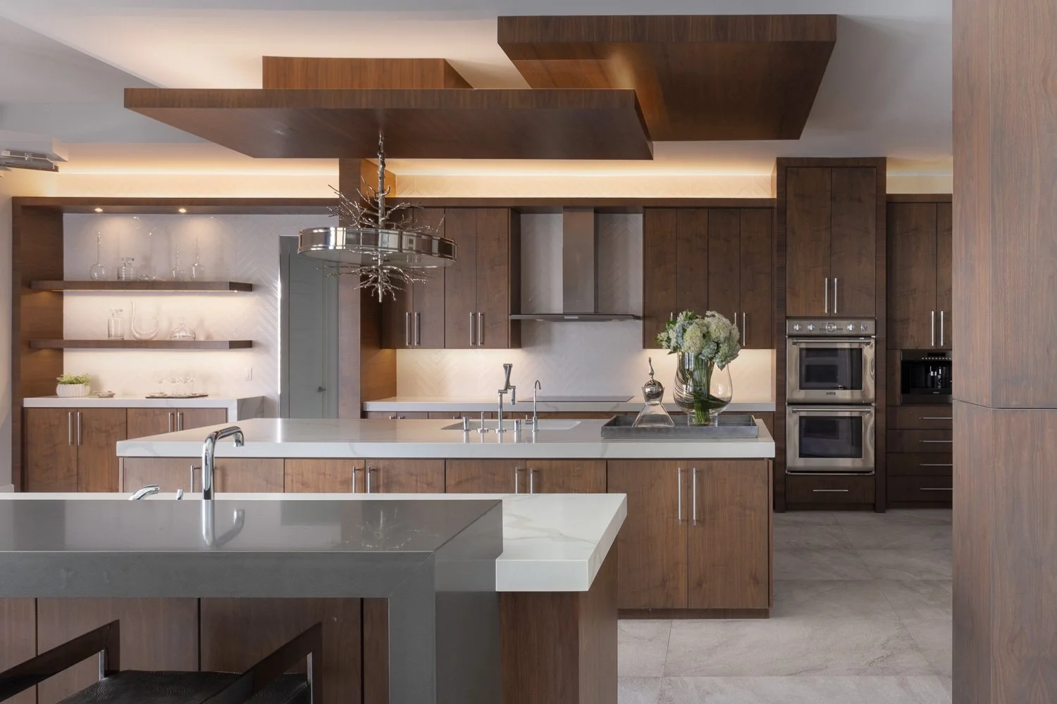 Modern kitchen design with walnut cabinets, white countertops and large island by LUXYSPACE Orange County