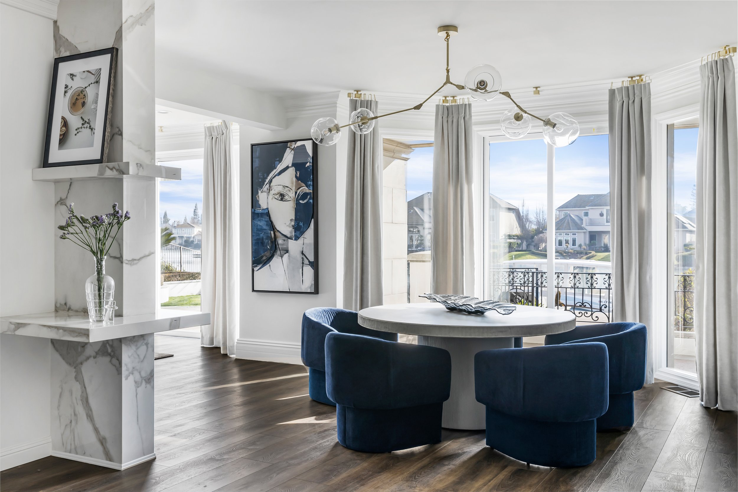 Breakfast nook with navy velvet chairs, round table and windows overlooking the lake in the Lakeside View remodel, designed by LUXYSPACE