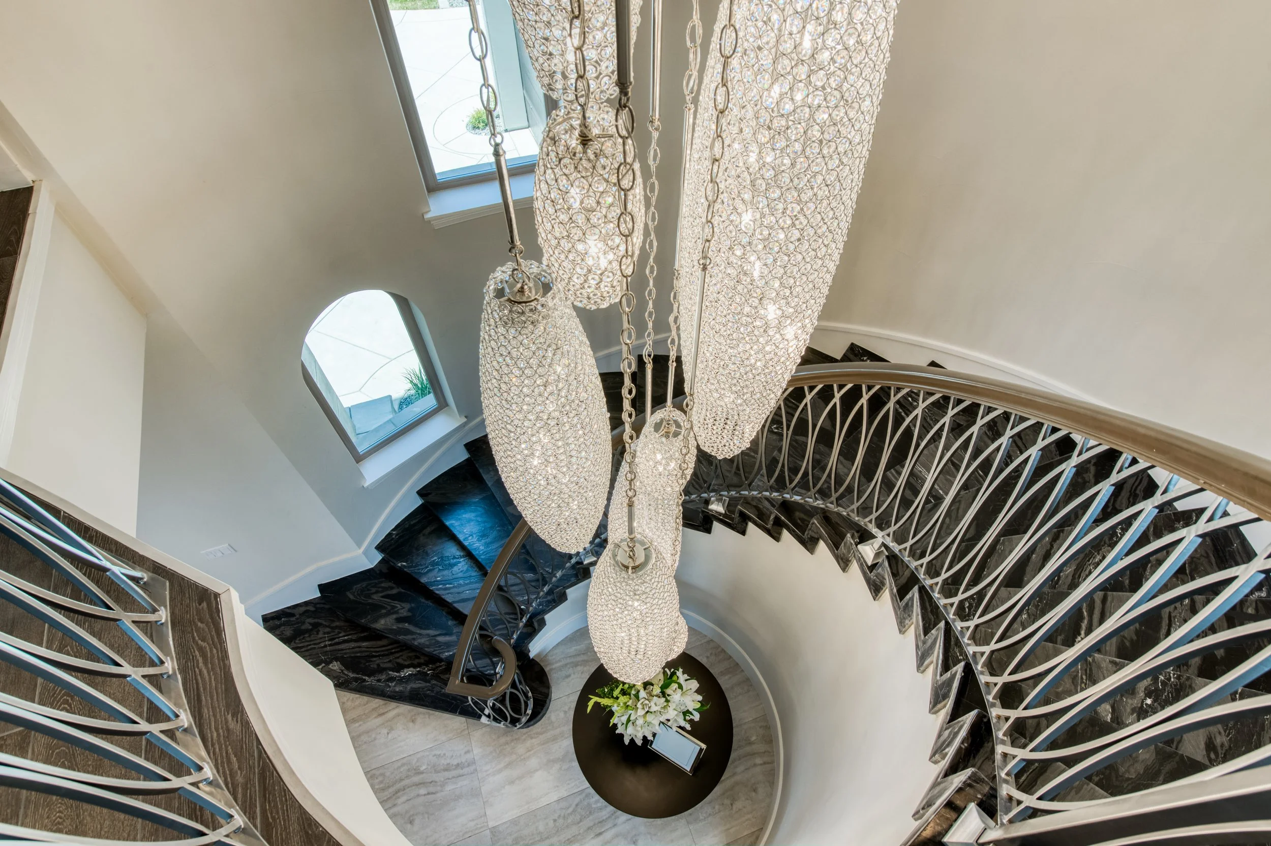 Grand spiral staircase with black marble steps and crystal chandeliers, LUXYSPACE luxury interior