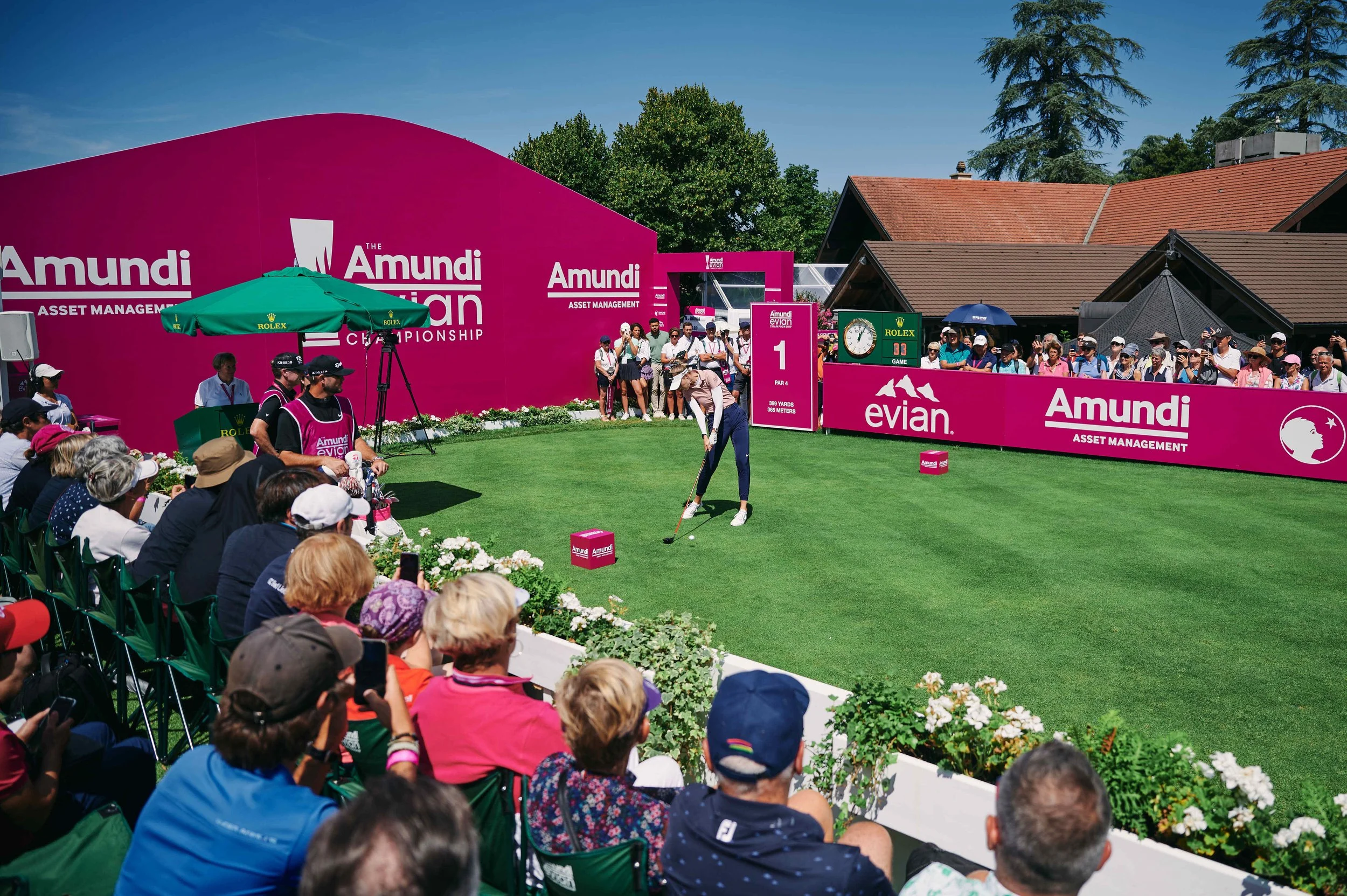 A professional golfer tees off in front of a large crowd at the first hole during the LPGA's Amundi Evian Championship at the Evian Resort Golf Club, a premier destination for our luxury golf itineraries in the Rhône-Alpes.