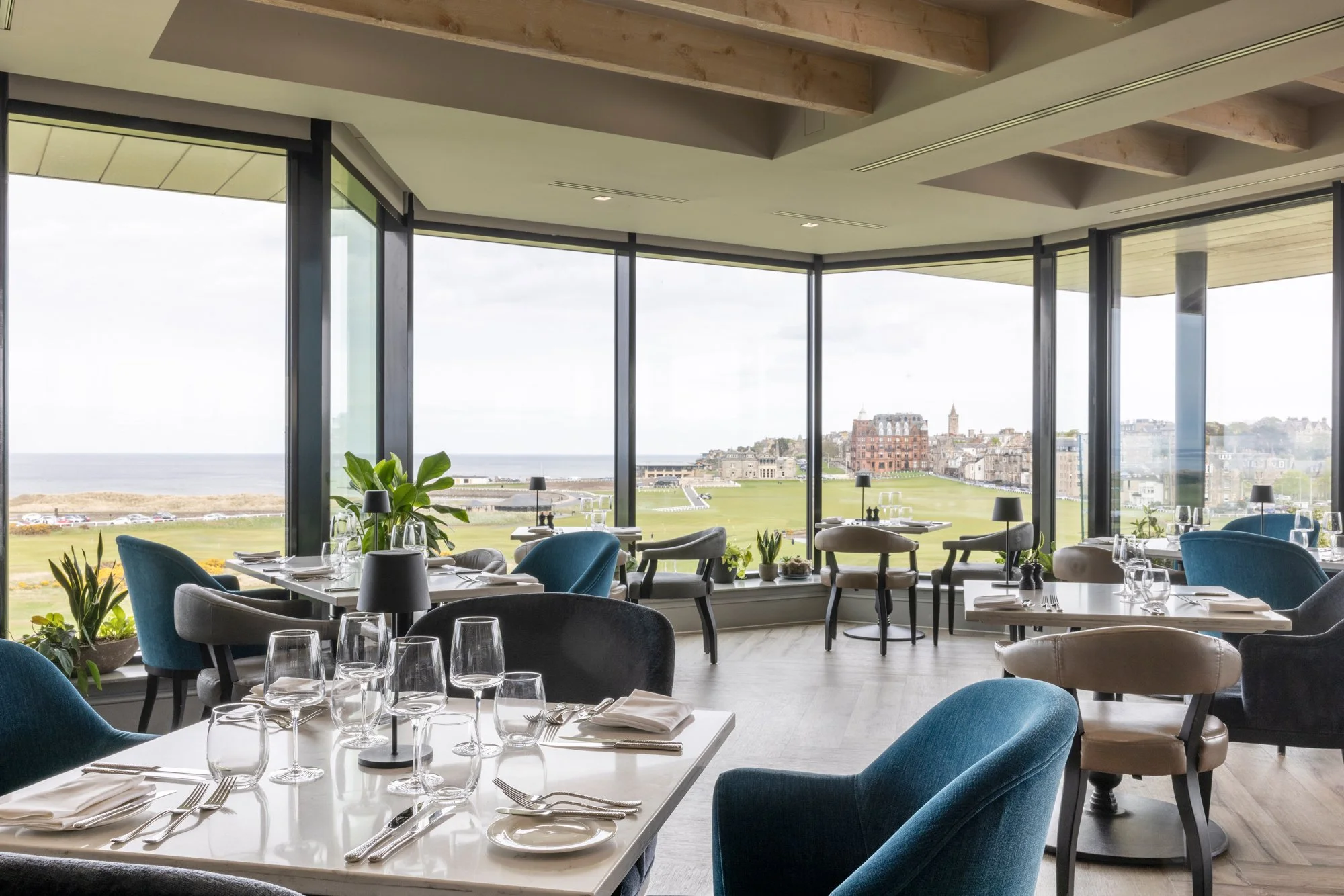 An elegant fine dining room with floor-to-ceiling windows at the Swilcan Loft inside the Old Course Hotel, offering panoramic views of St Andrews and perfectly capturing the Gourmet Golf experience on our luxury Scottish tours.