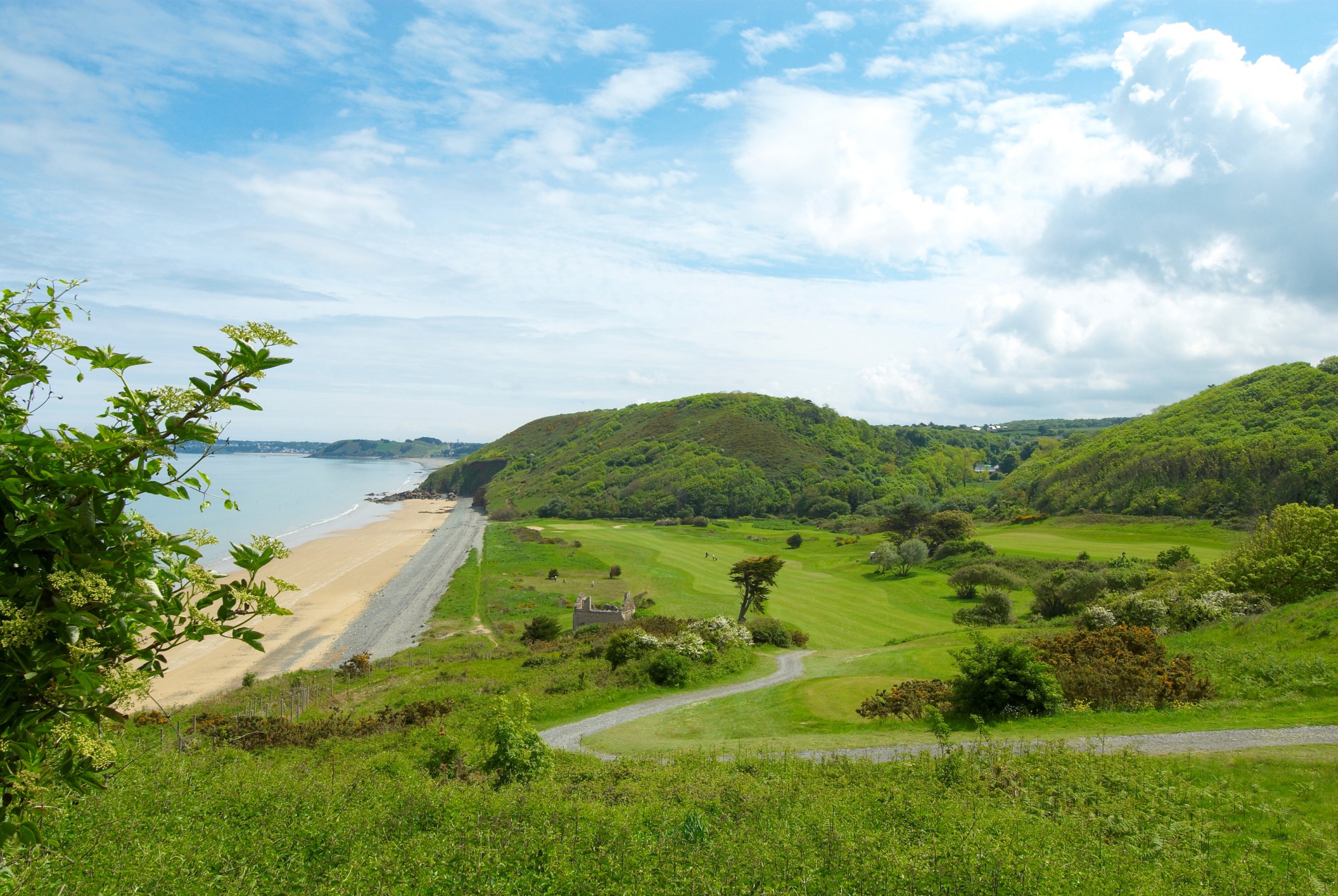 A spectacular coastal view of the lush green fairways at Golf Bluegreen Pléneuf-Val-André, situated right next to a sandy beach and the ocean, a highlight of our luxury golf vacations to Brittany, France.