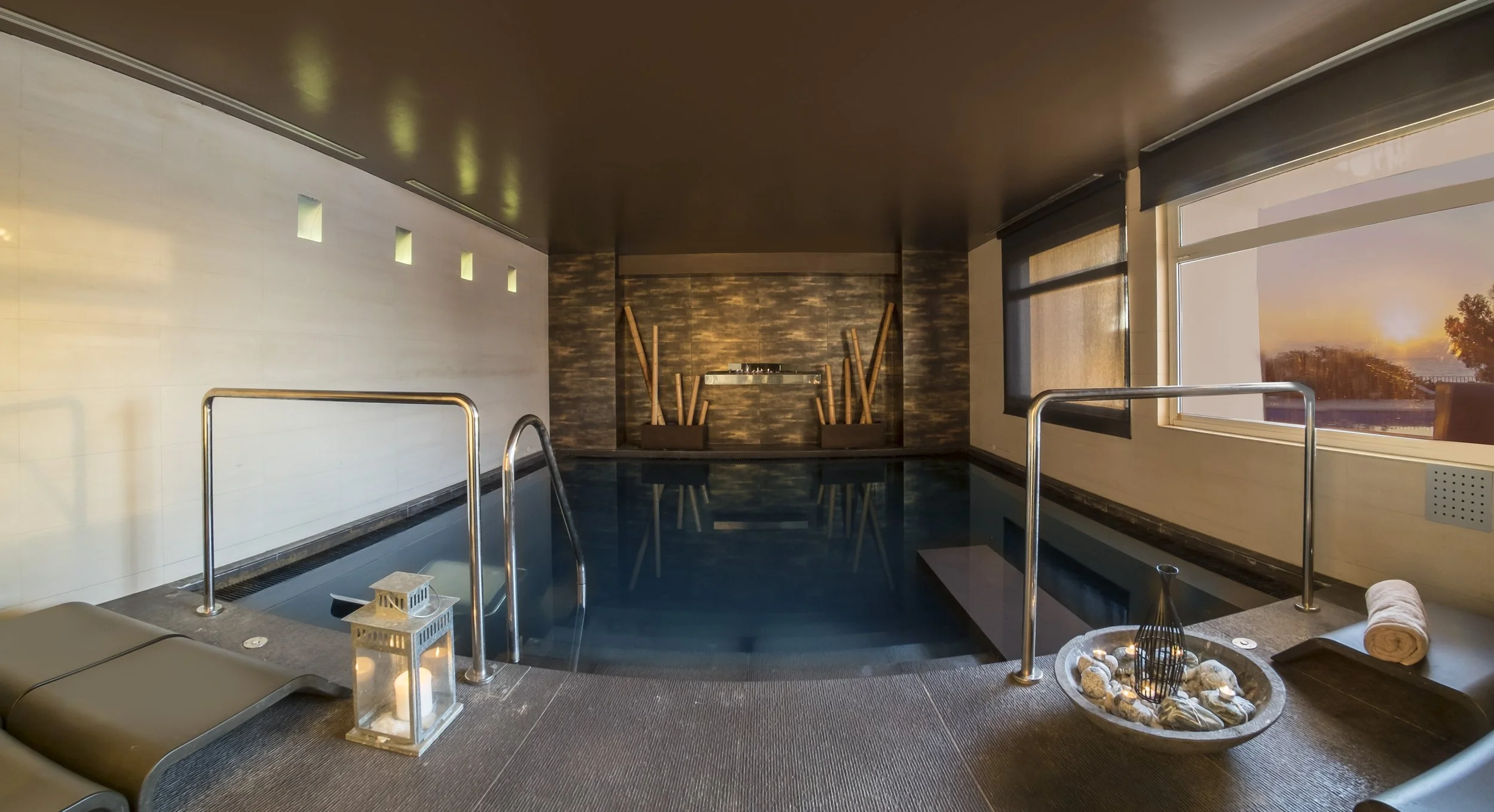 Indoor spa or hot tub area with large window showing sunset, relaxing decor, and candles.