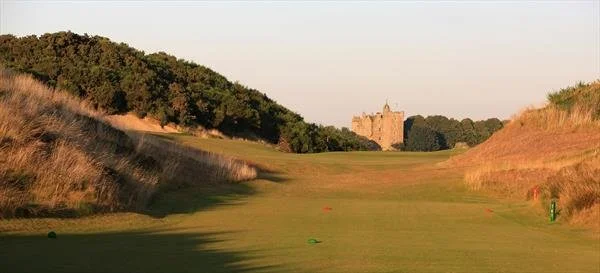 A golf course fairway with rolling hills and a castle in the background.
