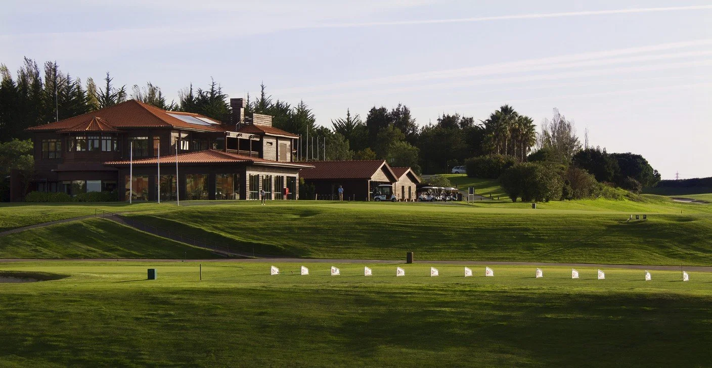 Golf course with a clubhouse and trees in the background