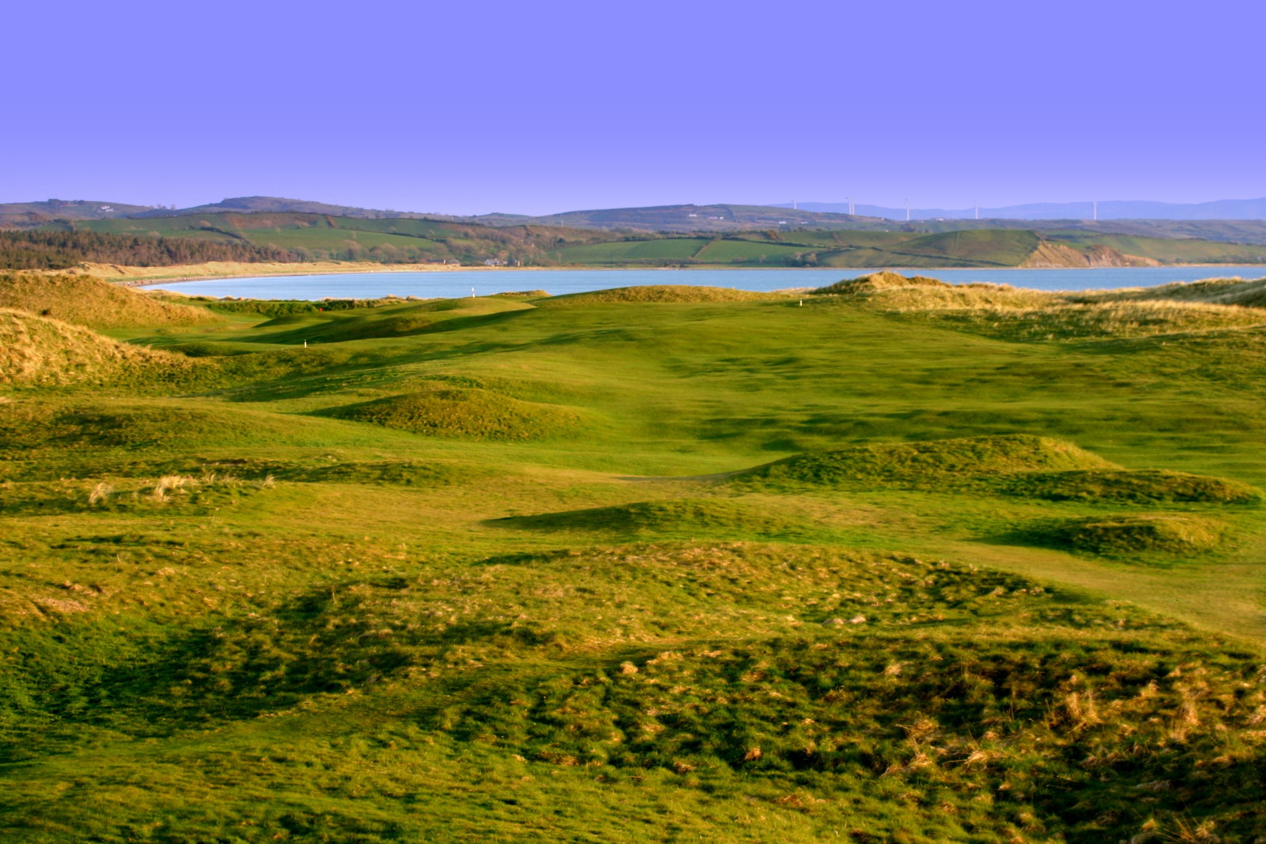 Expansive view of the rolling green links at Donegal Golf Club looking out over the bay, a beautiful and memorable course to include on custom golf vacations to Ireland.