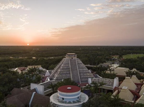 Aerial view of an ancient Mayan pyramid with jungle surroundings at sunset.