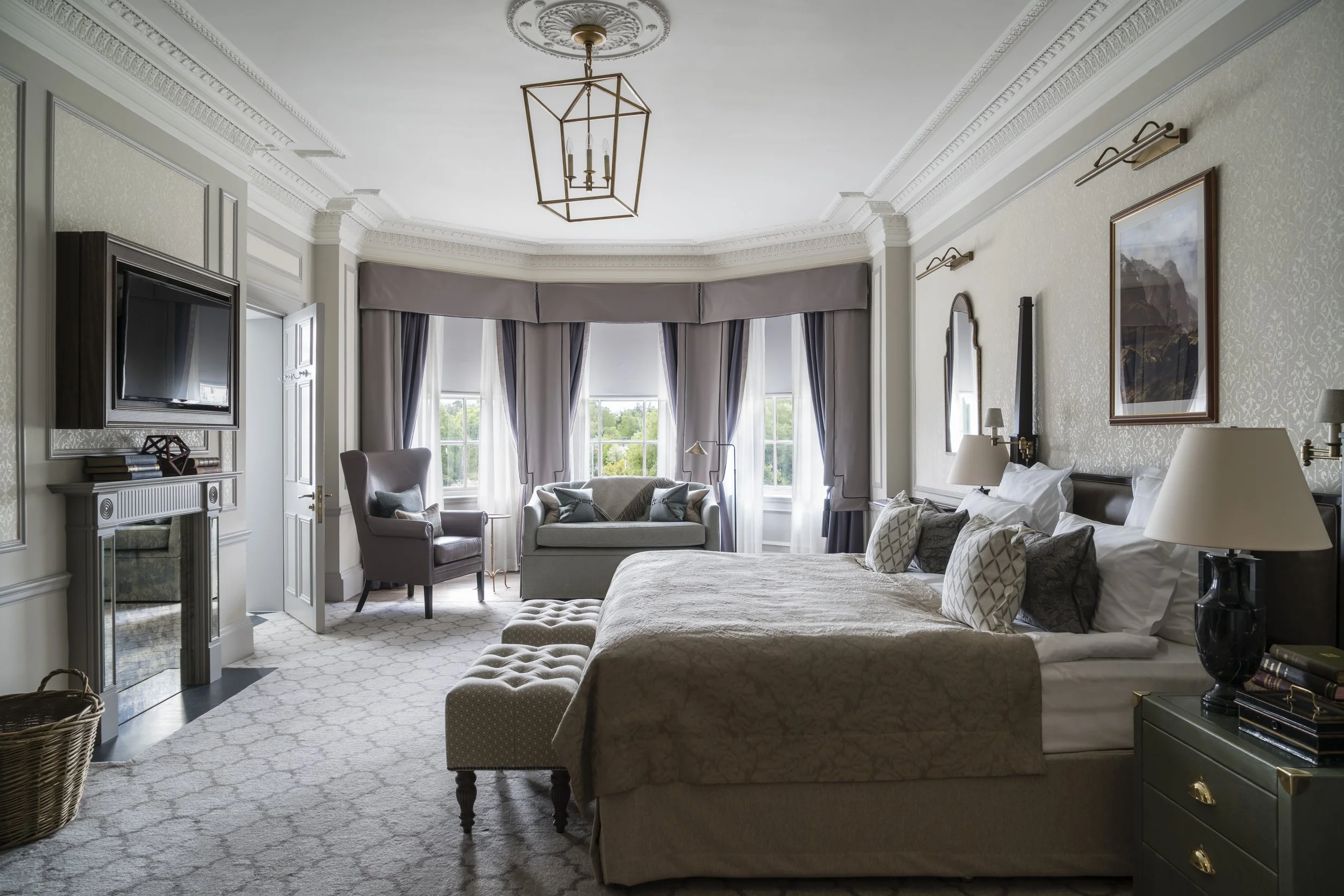 Luxurious bedroom with canopy bed, armchair, sofa, and large windows with curtains.