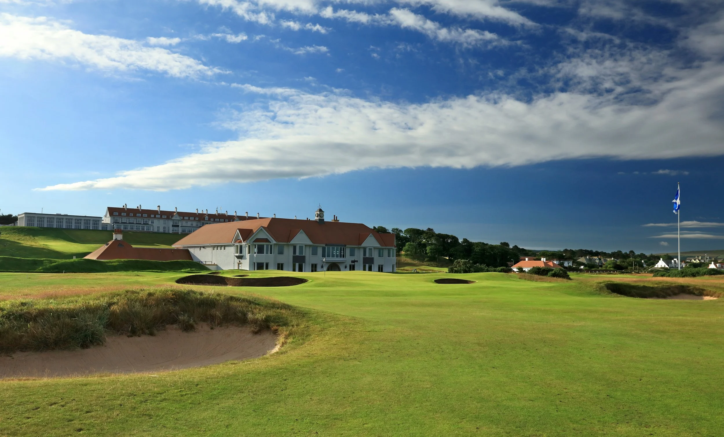 A view of the 18th green and bunkers on the Trump Turnberry Ailsa Championship Course, with the historic Turnberry Golf Club and Hotel in the background, a bucket-list destination on our luxury escorted golf tours to Scotland's Ayrshire Coast.