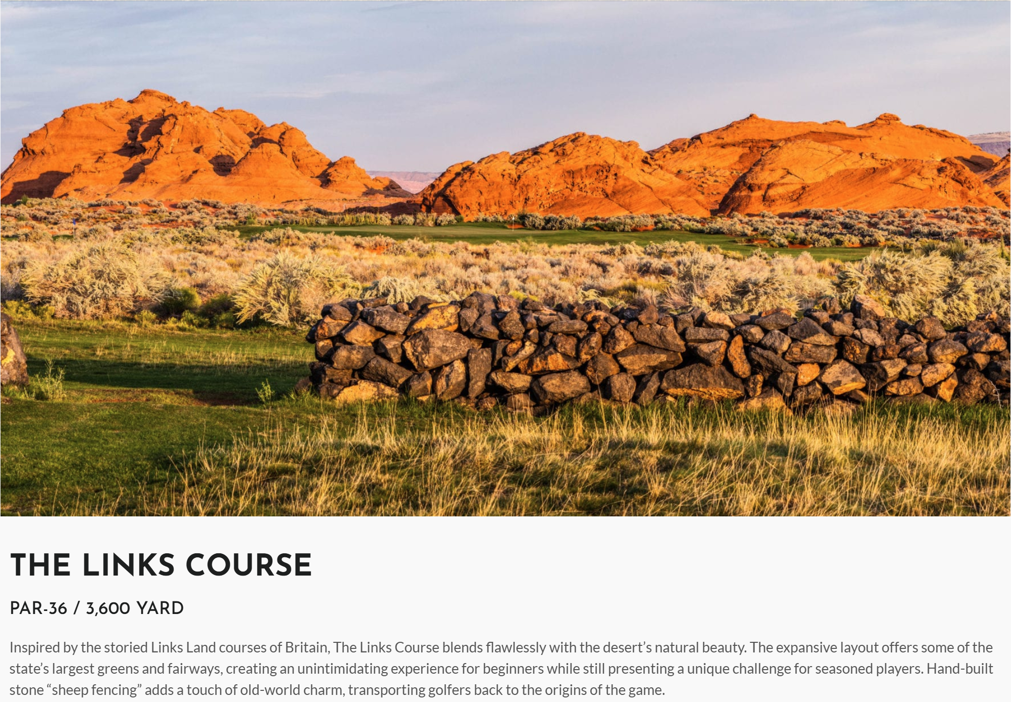 Scenic landscape of desert terrain with red rock formations, grassy fields, and a stone sheep fencing wall in the foreground.