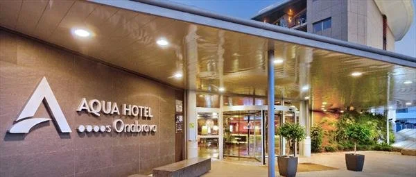 Exterior view of Aqua Hotel Ondarreta, showing its entrance with a large sign and potted plants.