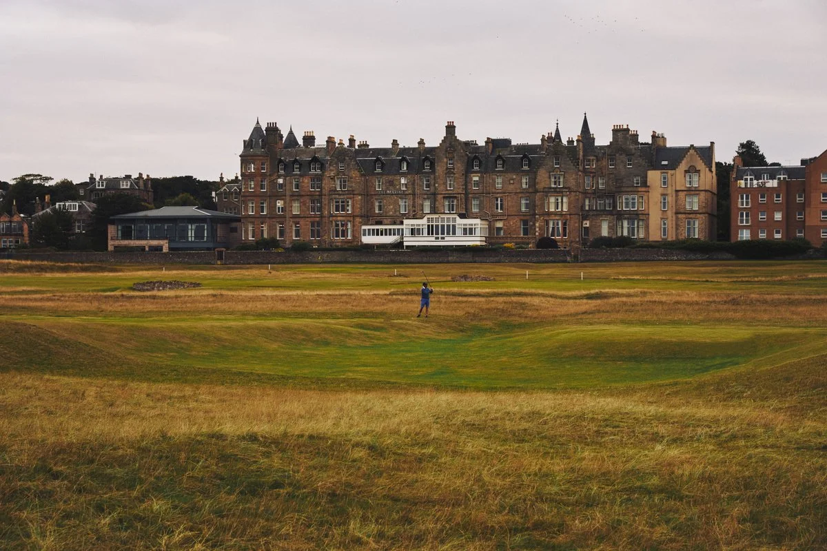 A golfer plays a shot from the rugged links fairways of the North Berwick West Links, with the grand Marine North Berwick hotel standing proudly in the background, a historic destination on our luxury escorted golf tours in Scotland.
