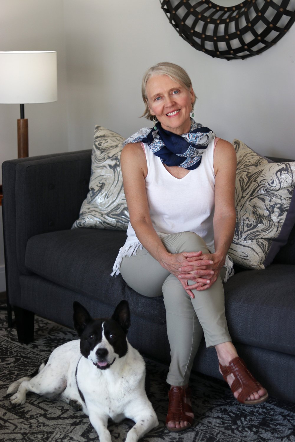 A transformational life coach sitting on the sofa in her office with her dog laying on the floor