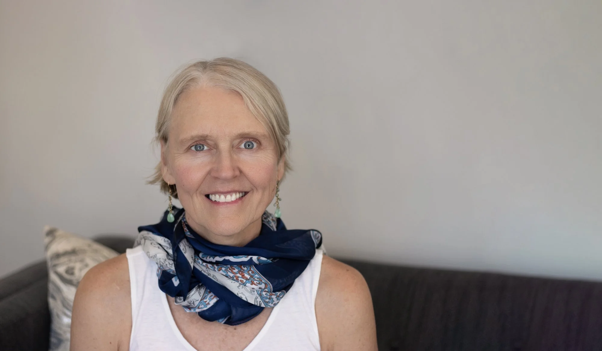 Transformational life coach Rebecca Saxon wearing a blue silk scarf on a sofa
