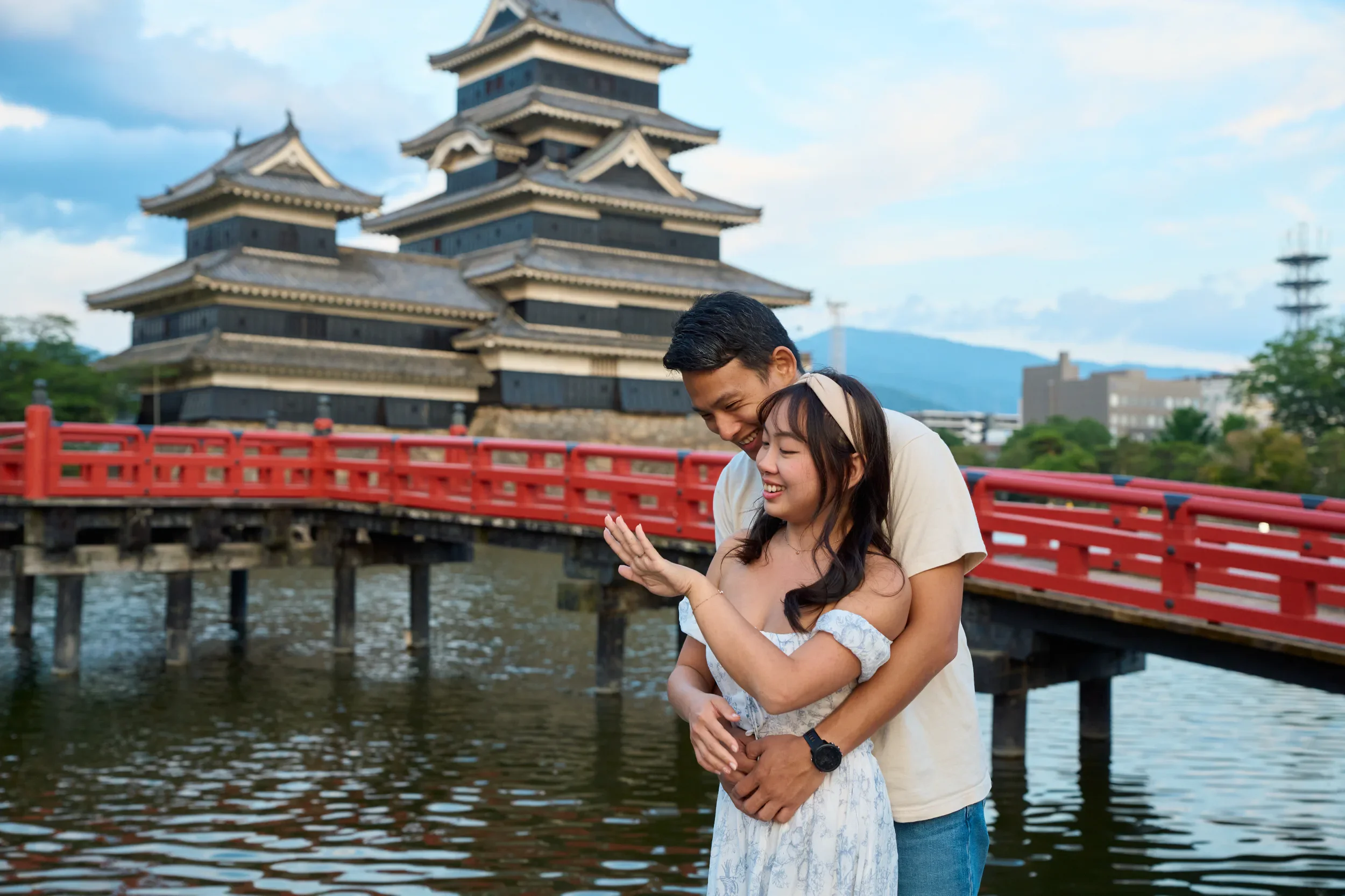 Newly engaged couple laughing together near the red bridge at Matsumoto Castle