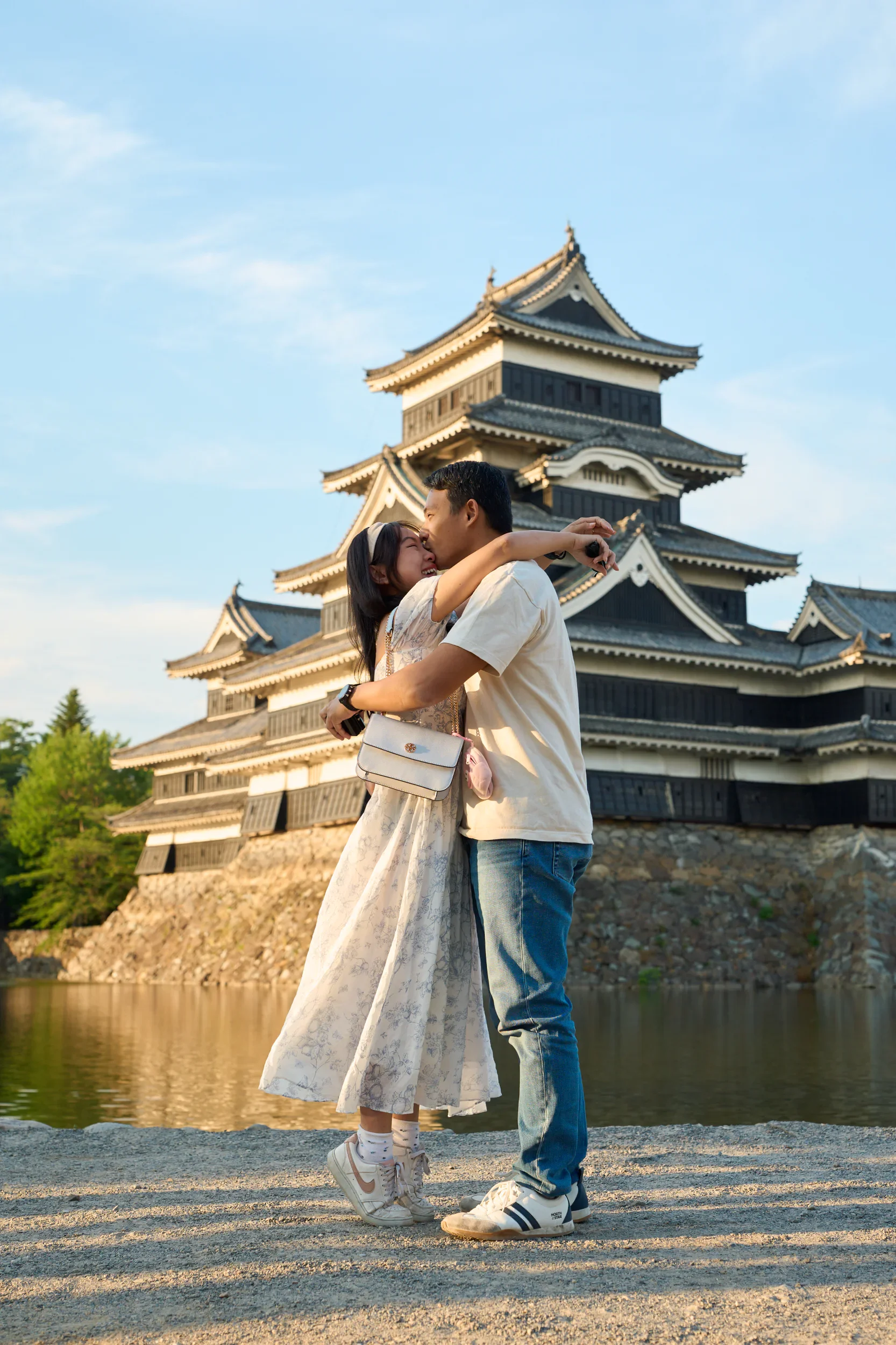 Newly engaged couple embracing in front of Matsumoto Castle at sunset