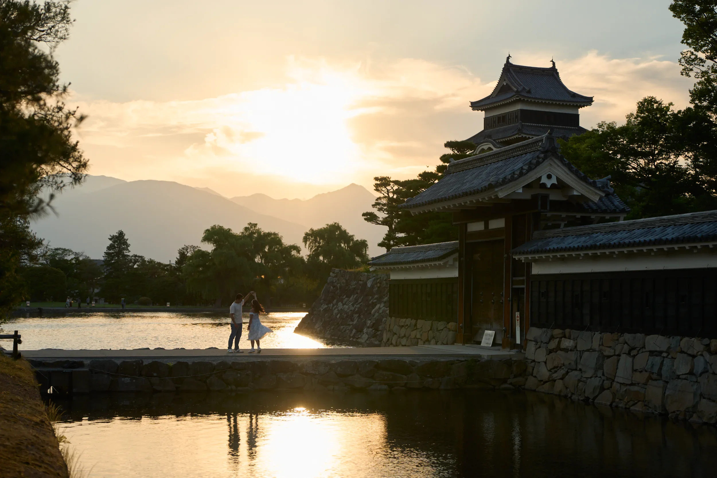 Silhouette of a couple dancing by the moat at Matsumoto Castle at sunset