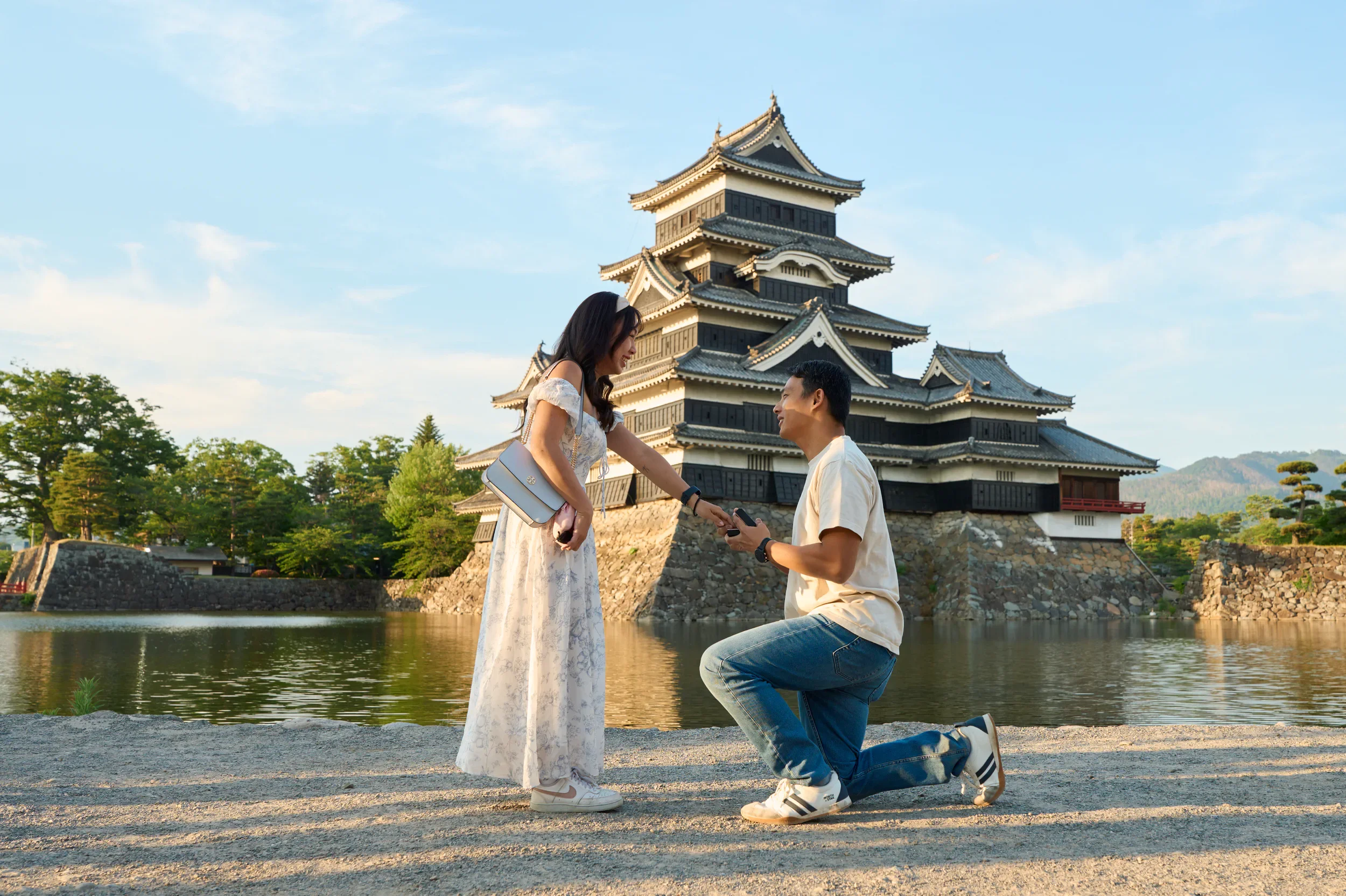 Groom kneeling and presenting an engagement ring in front of Matsumoto Castle