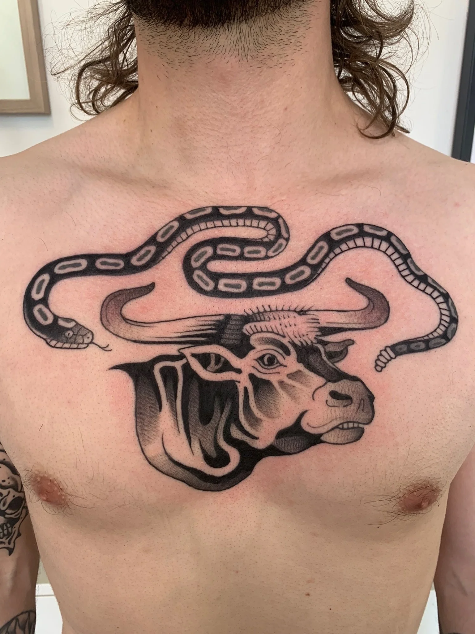 Tattoo of a buffalo with a snake coiled around its horns on a person's chest, made at Thanks Tattoo