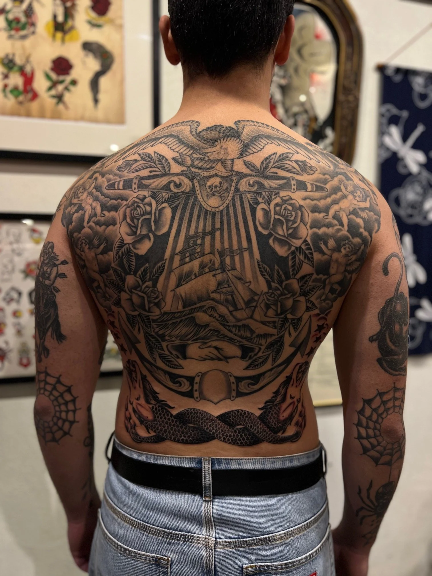 Back tattoo featuring a bird, roses, a ship, and a snake, along with various decorative elements, made at Thanks Tattoo.