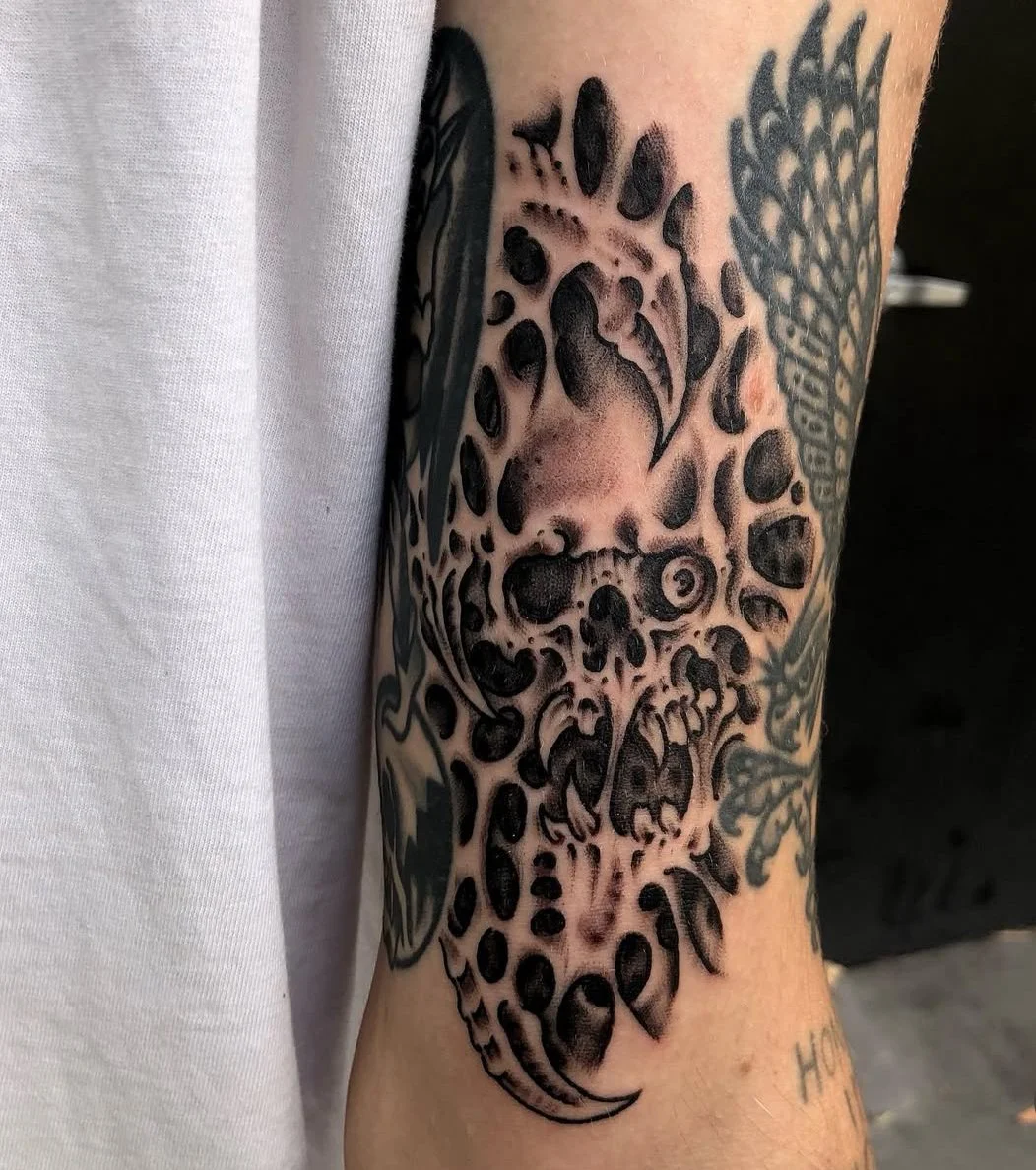 Tattoo of a leopard face with skull elements and leopard spots on person's arm, made at Thanks Tattoo