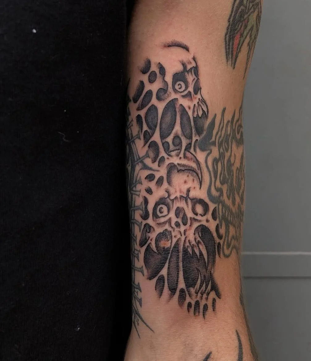 Tattoo of a leopard's face and skull on an arm, rendered in black ink with detailed shading and line work., made at Thanks Tattoo