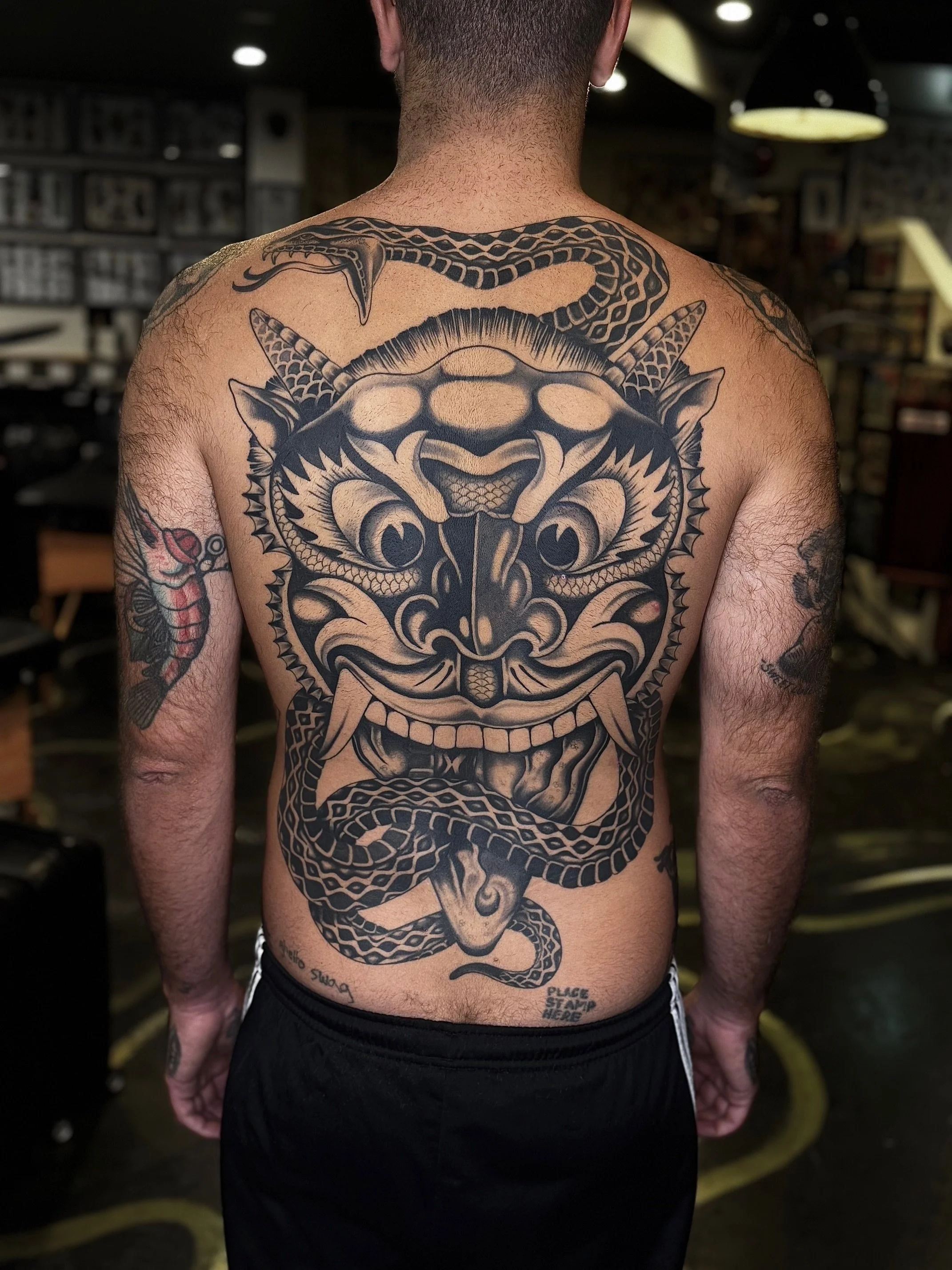 A man with a large, detailed traditional Japanese-style dragon tattoo covering his back, with a snake tattoo on his left arm and a shrimp tattoo on his right arm, made at Thanks Tattoo
