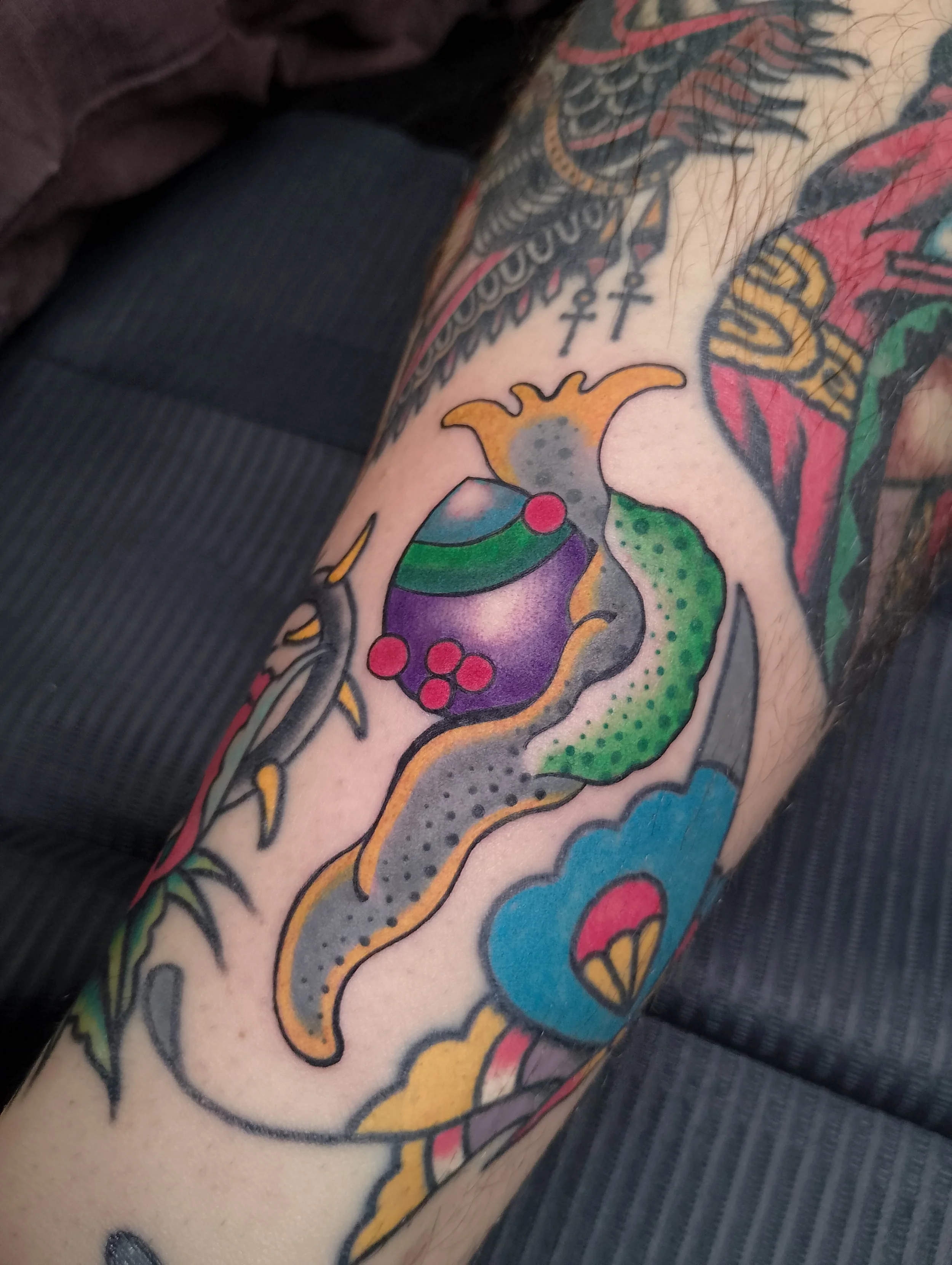 Colourful tattoo of a snake wrapped around a traditional-style ornament with a cloud and heart at the bottom, made at Thanks Tattoo
