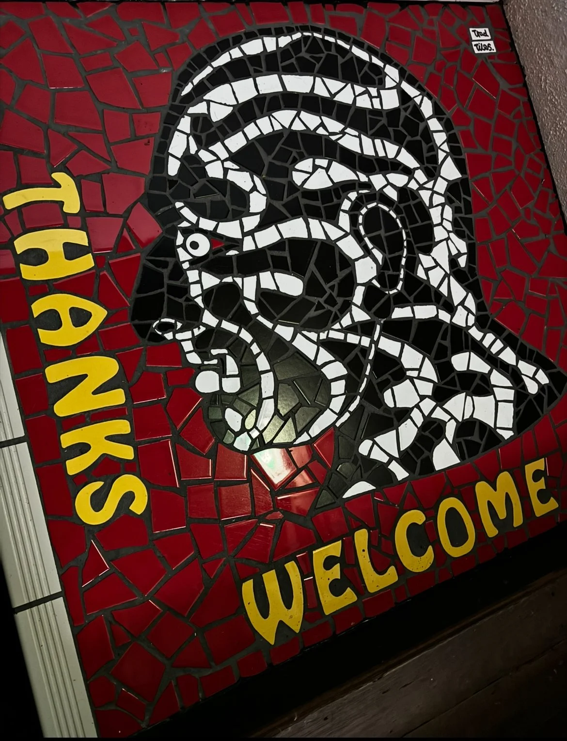 Colorful mosaic mural of a man's face with white scissors and a comb, with yellow text reading "THANKS" on the left and "WELCOME" at the bottom.