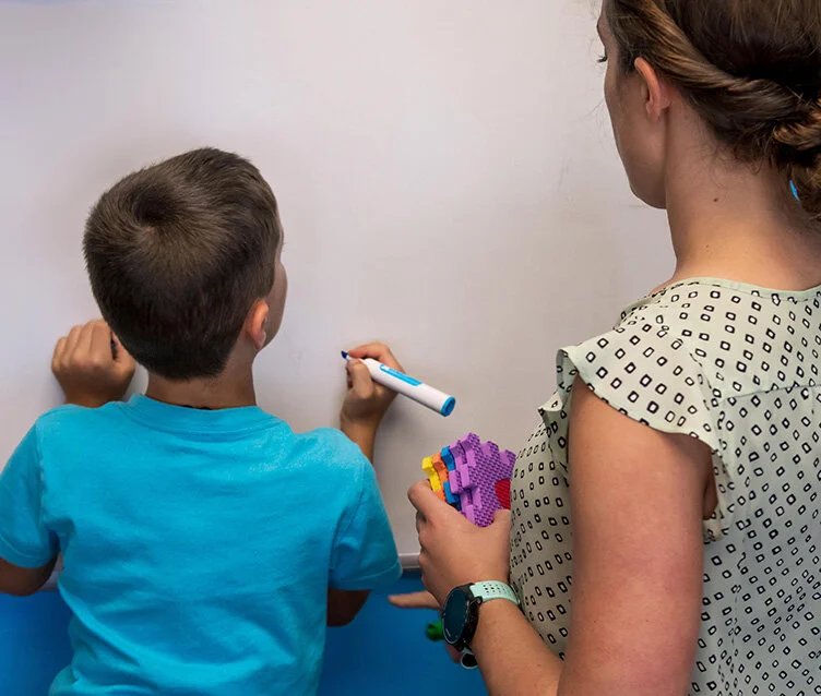 Boy writing with occupational therapist
