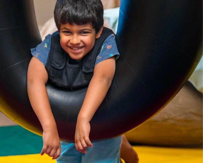 Smiling boy playing in a tube swing during sensory occupational therapy