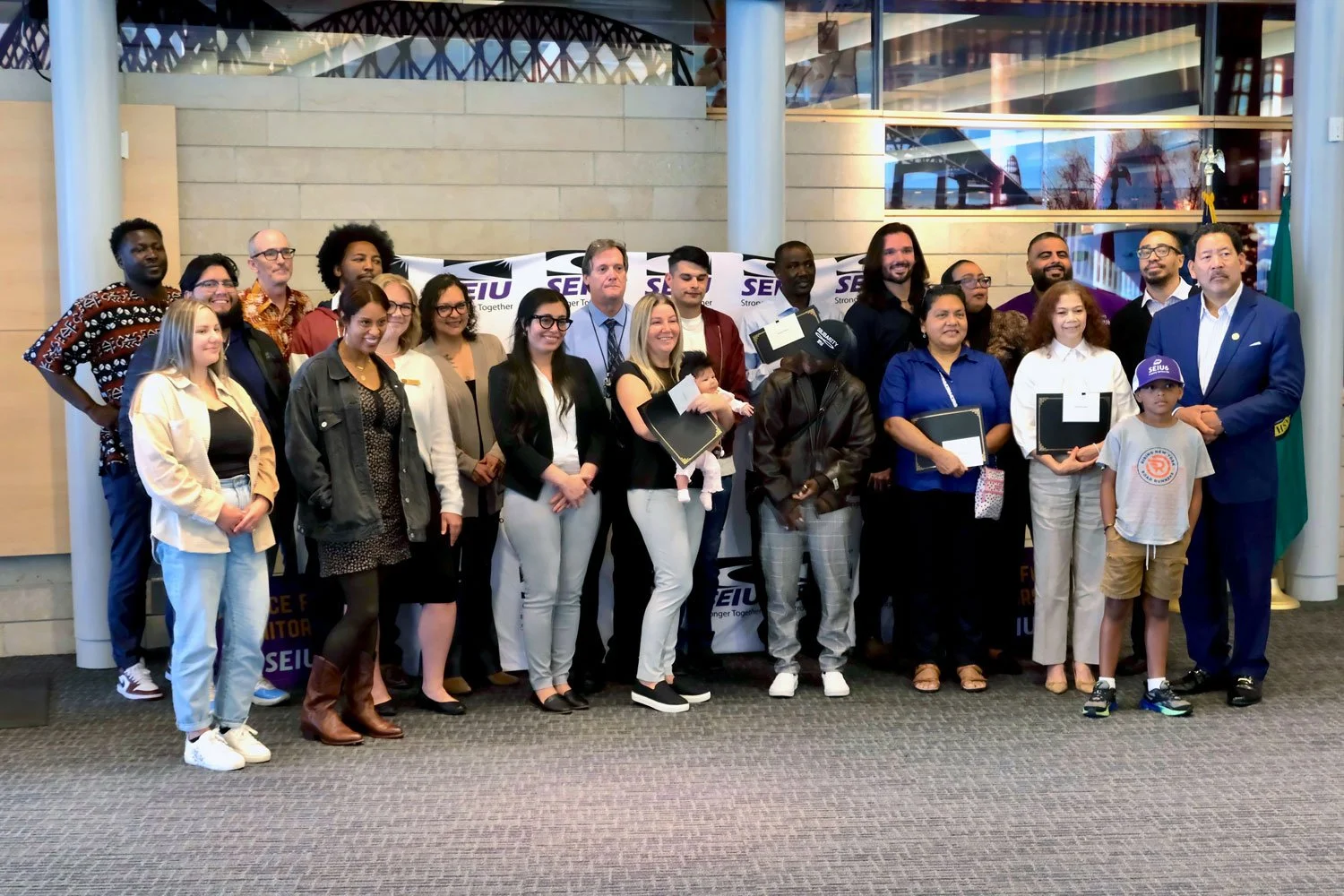 diverse group of smiling janitorial / property service workers standing side by side within a building environment by side