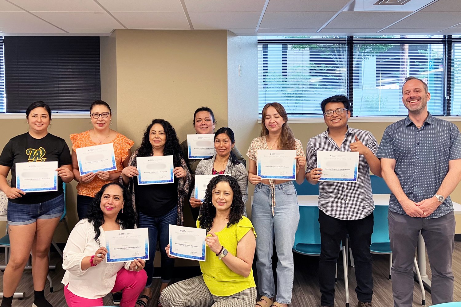 diverse group of individuals smiling and holding certificates of completion having taken an English Skills program at PCC