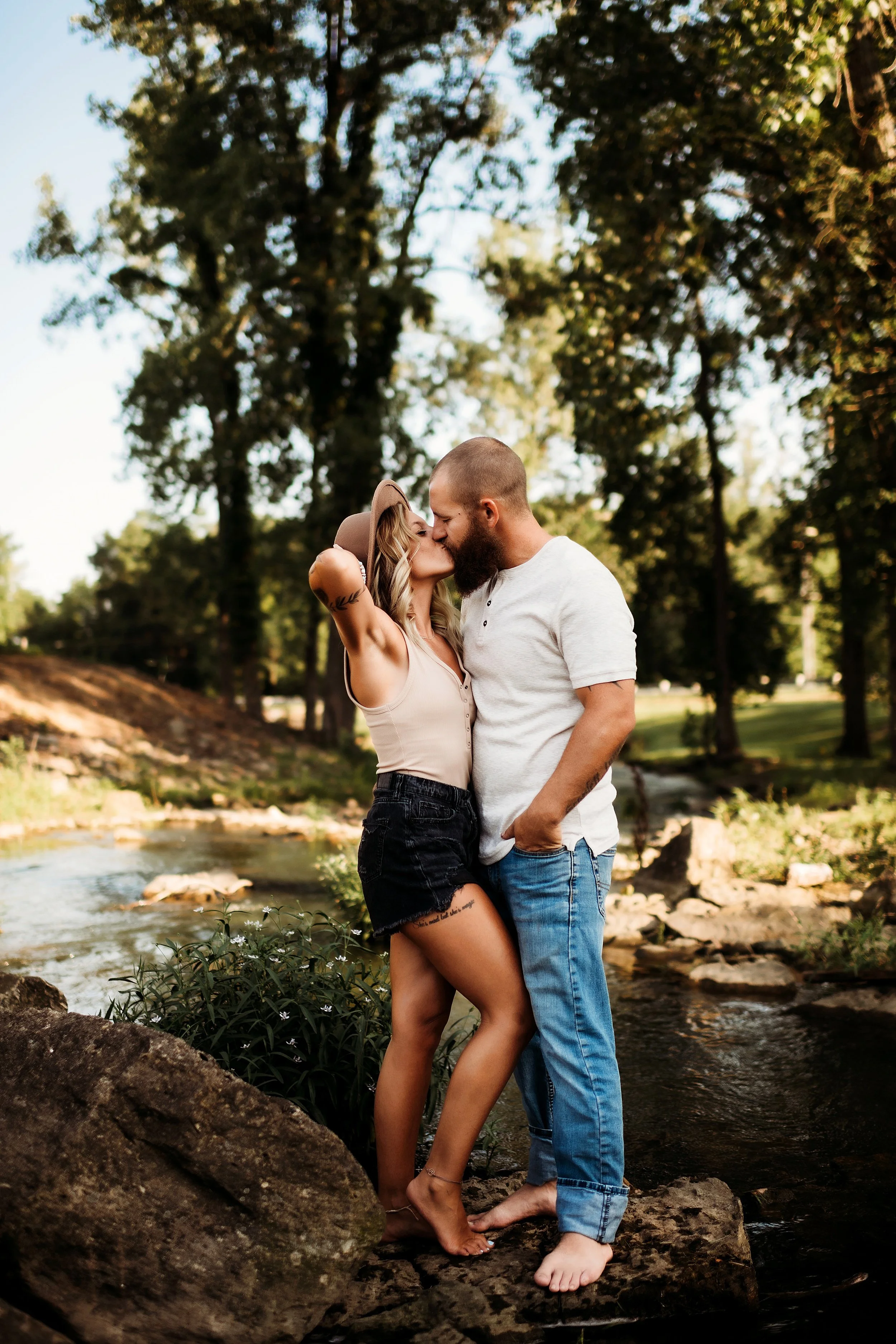 couple kissing in creek at sunset