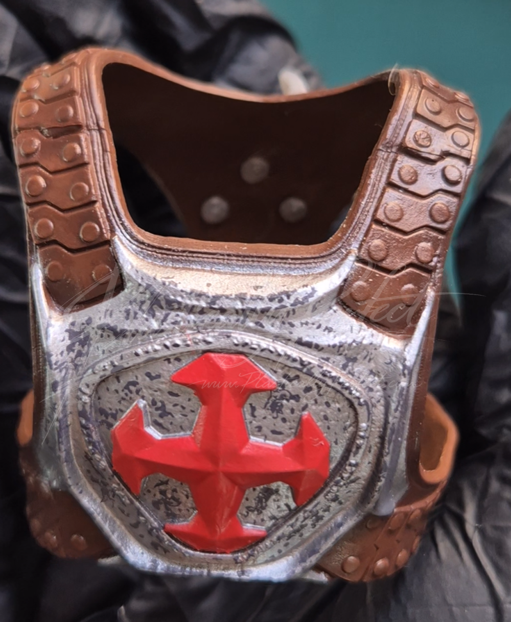 One of two close up shots of the chestpiece, which features a metal breastplate held fast by rivetted faux leather (plastic) straps and buckles.  This piece feels cohesive to the rest, and the photograph shows it removed from the He-Man doll.