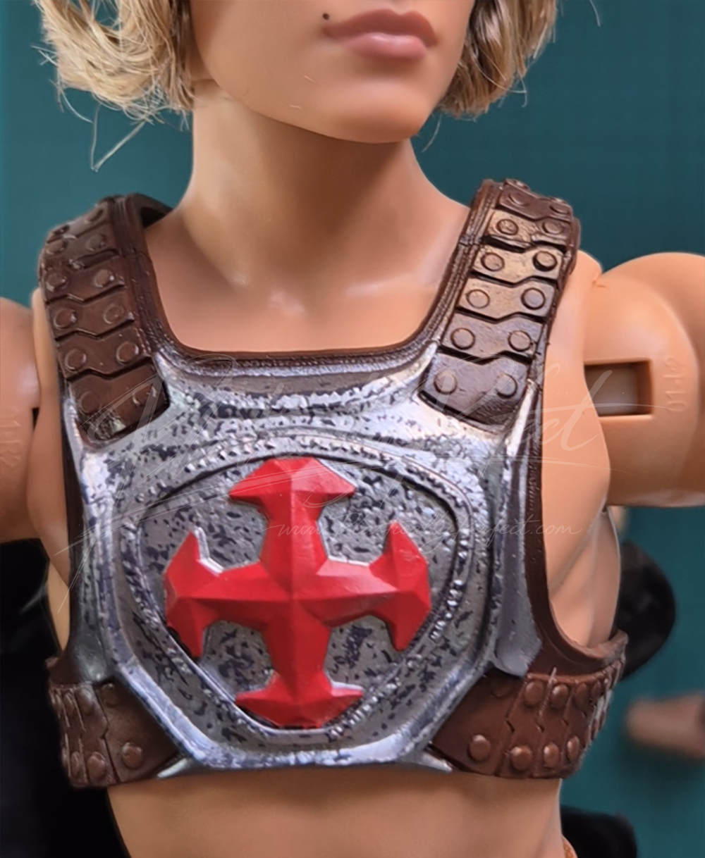 One of two close up shots of the chestpiece, which features a metal breastplate held fast by rivetted faux leather (plastic) straps and buckles.  This piece feels cohesive to the rest, and the photograph shows it on the He-Man doll.