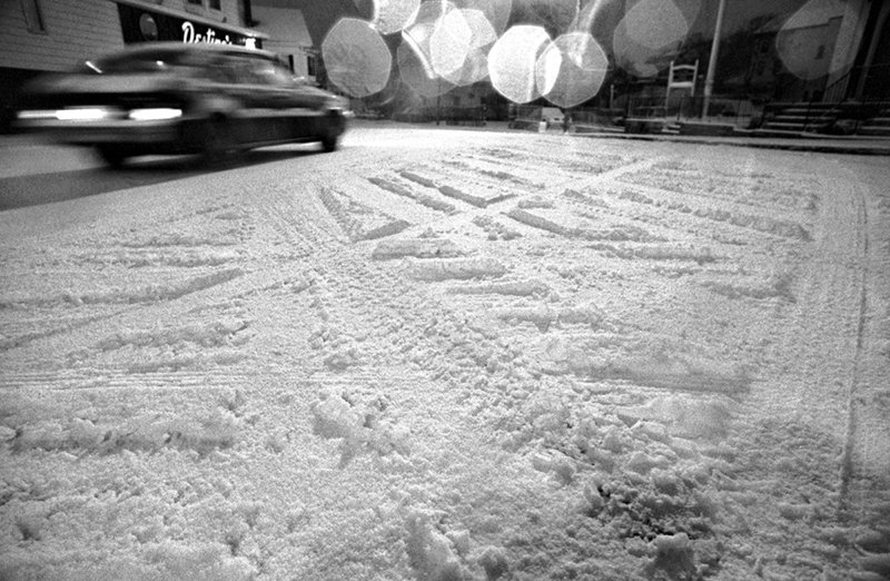   [7] A car travels along snow-covered Prospect Street in Gloucester this morning, 1984. Photograph by Kenn Shrader. &nbsp; 