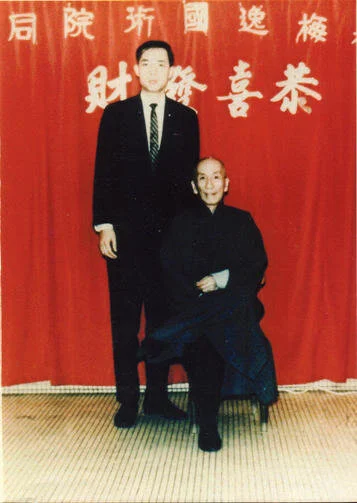 Grandmaster Moy Yat standing beside his teacher, Grandmaster Yip Man.