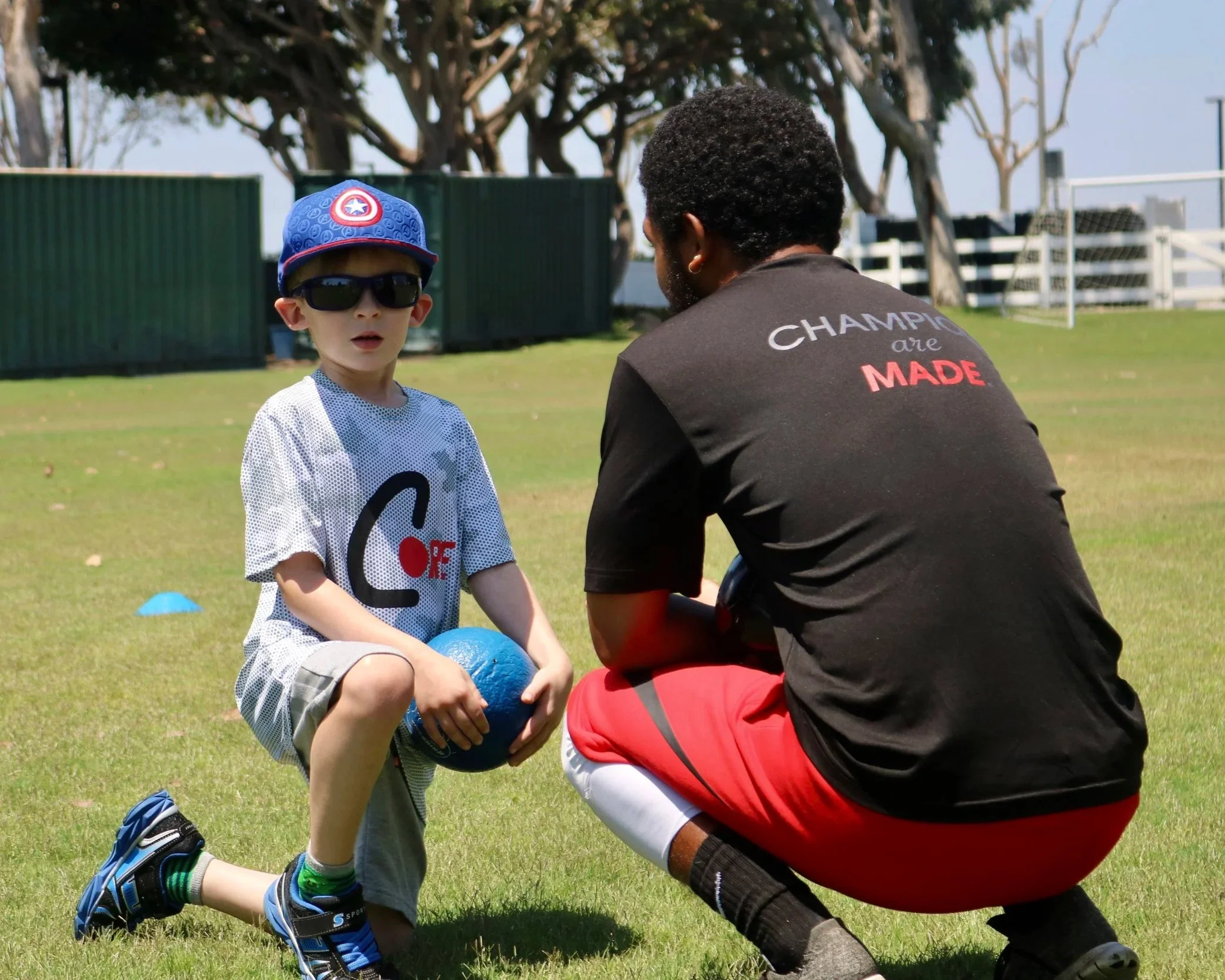 CORE coach talking with a young camper during outdoor sports camp.