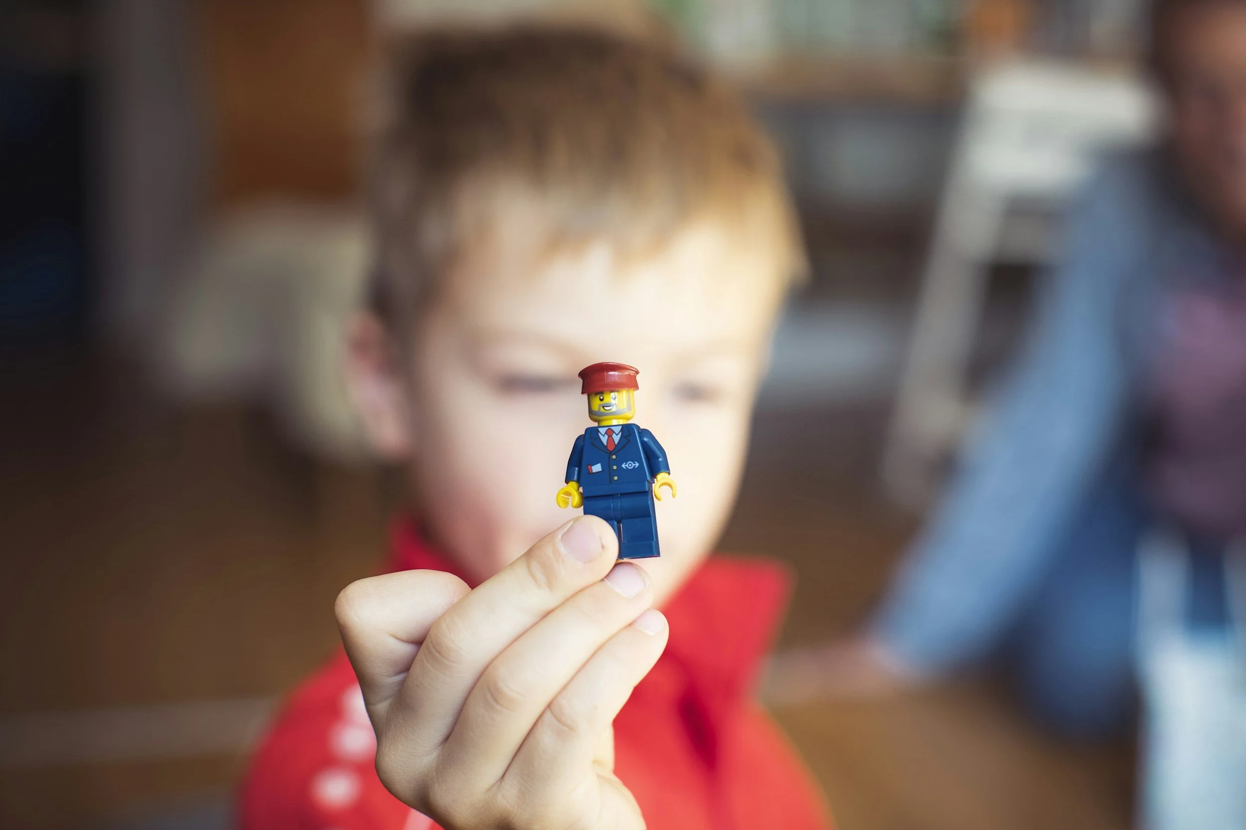 A child holds up a blue-suited LEGO minifigure for people seen or imagined.