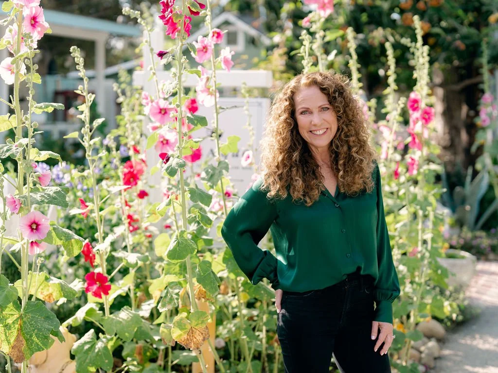 Jeanine Mouchawar, parenting coach for parents of teens, standing in a garden with pink flowers